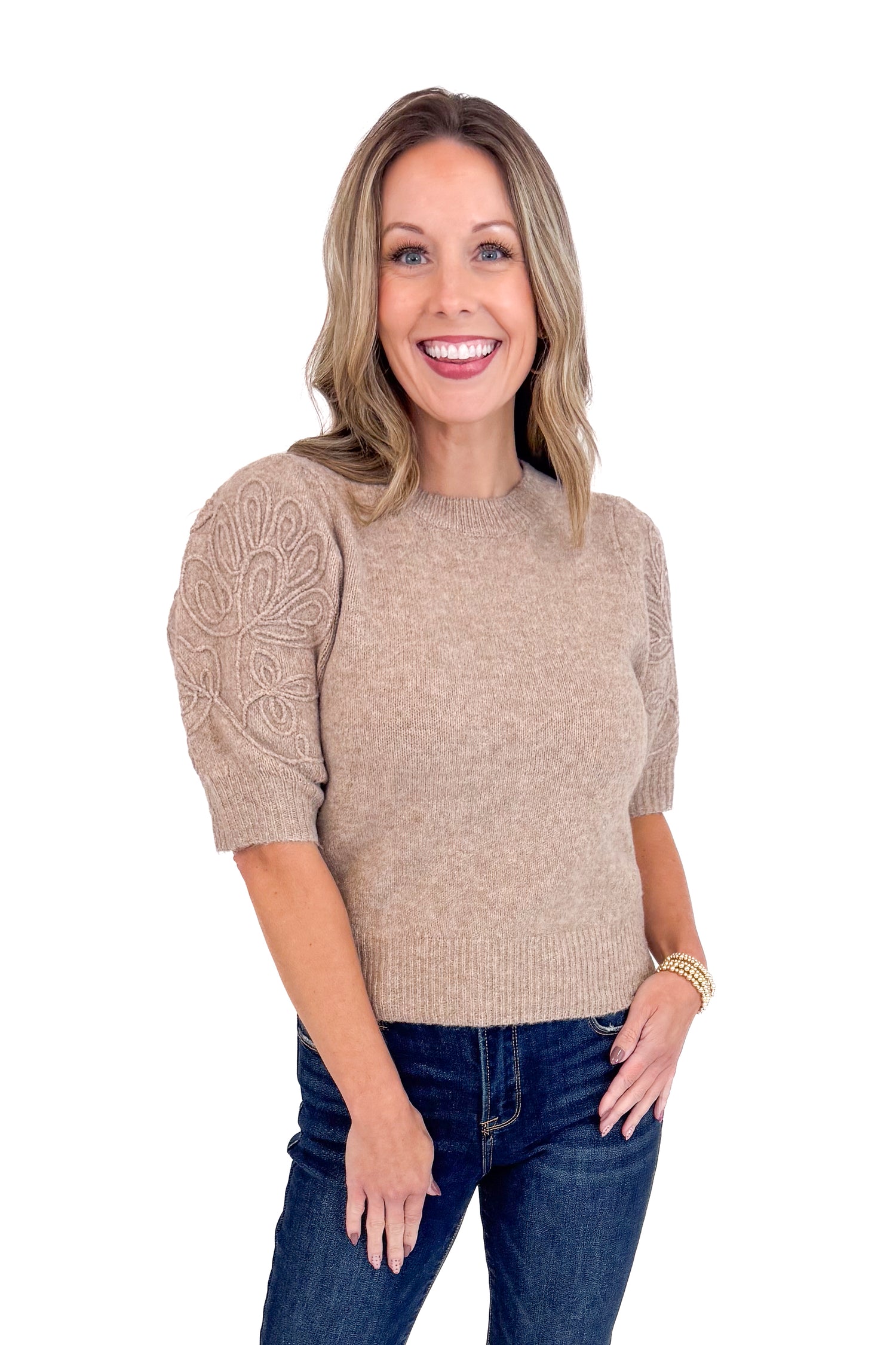 Woman wearing a beige sweater with lace sleeves on a white background