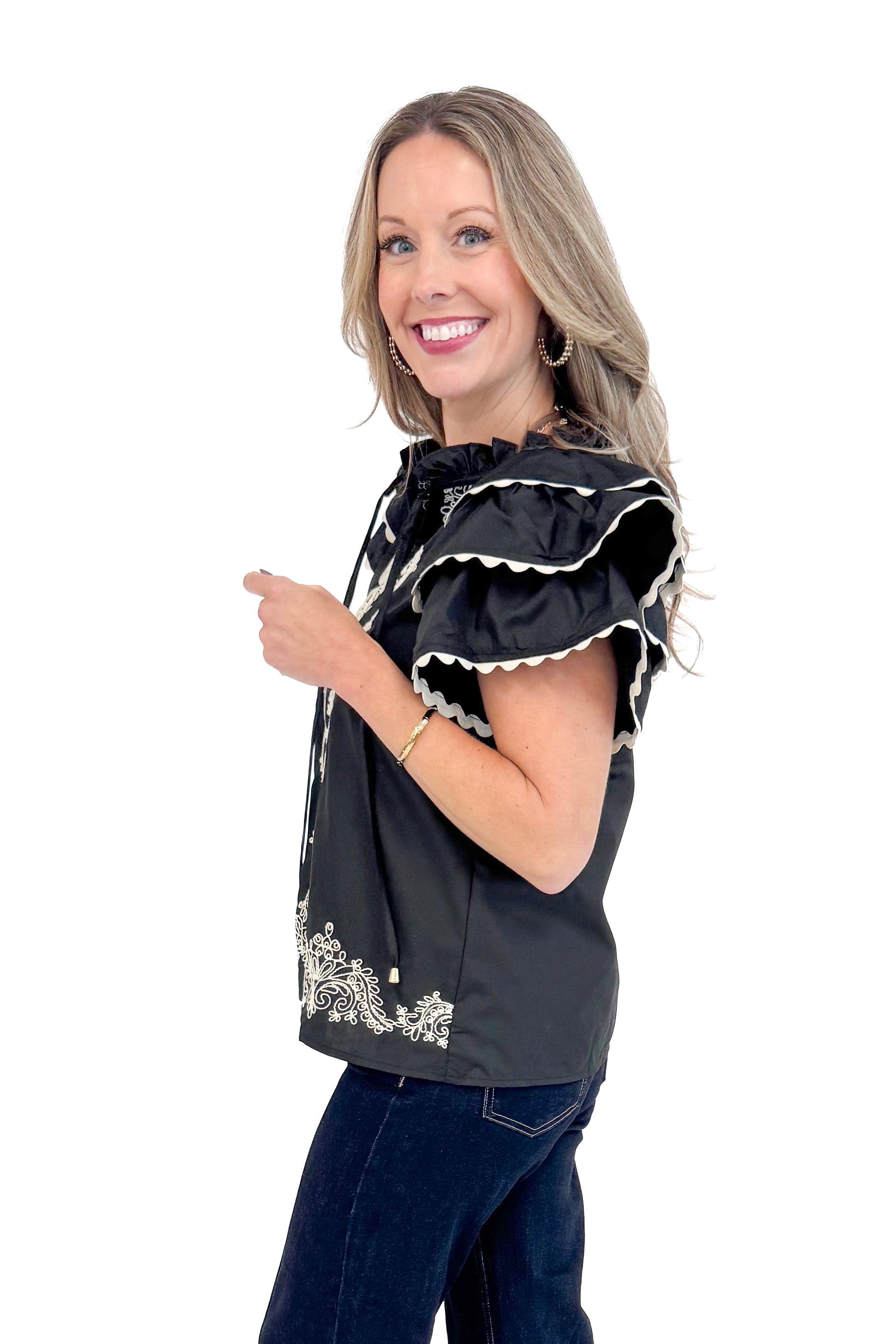 Side view of woman wearing Black Center Embroidered Ruffle Sleeve Top by Entro and blue jeans.