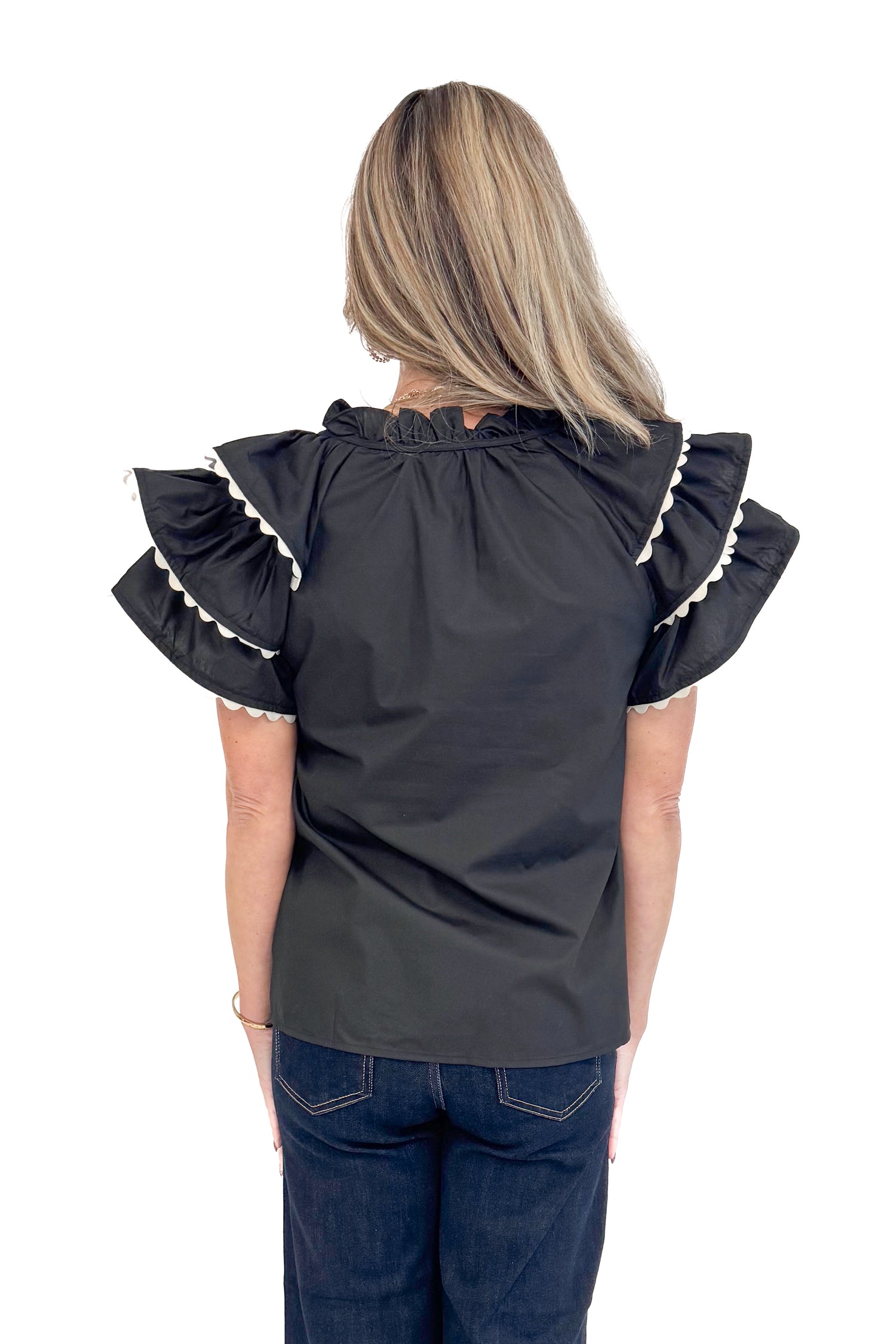 Back view of woman wearing Black Center Embroidered Ruffle Sleeve Top by Entro and blue jeans.