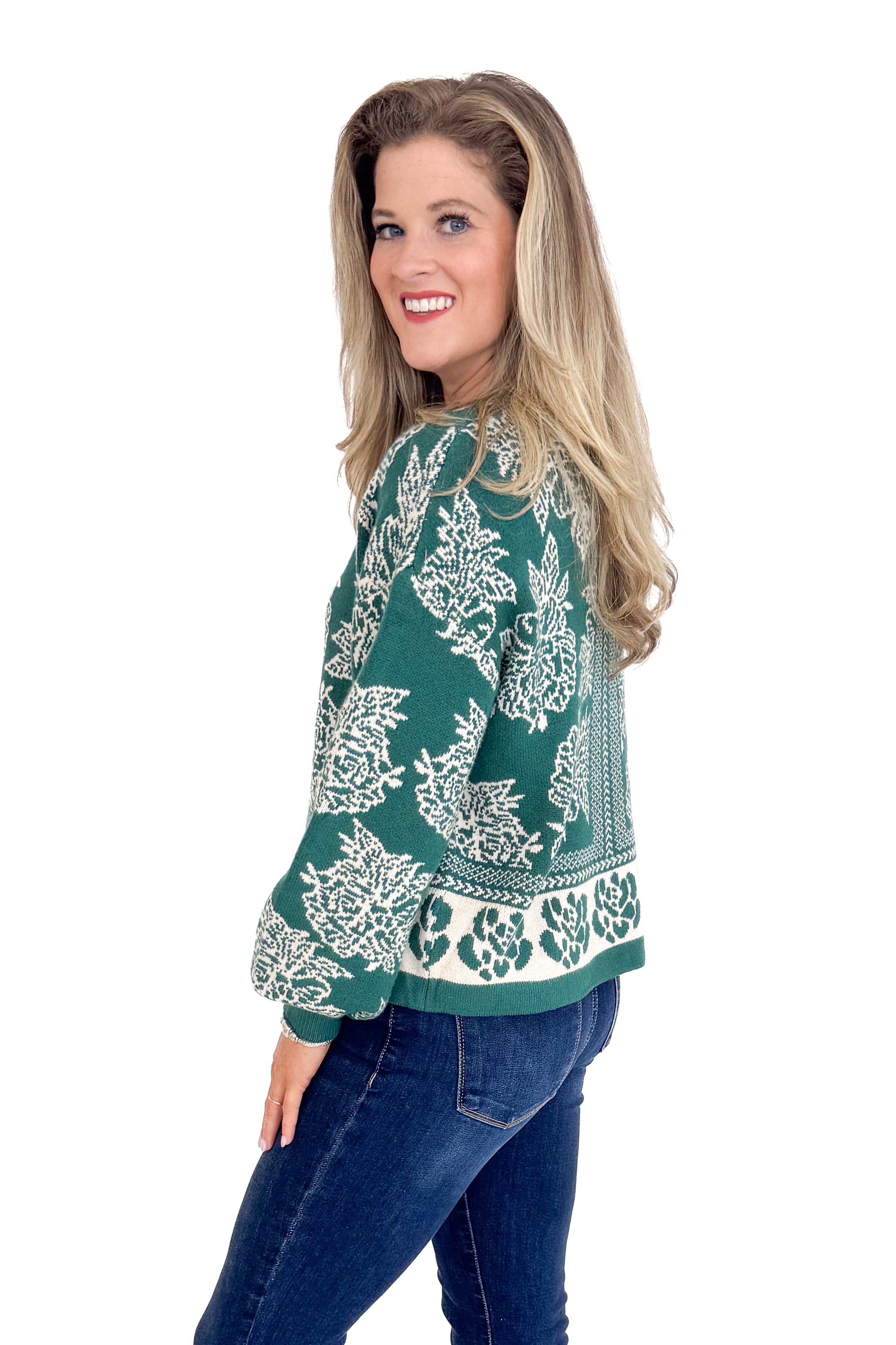 Woman wearing a patterned sweater and jeans on a white background