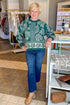 Woman wearing a green patterned sweater and blue jeans standing in a store.