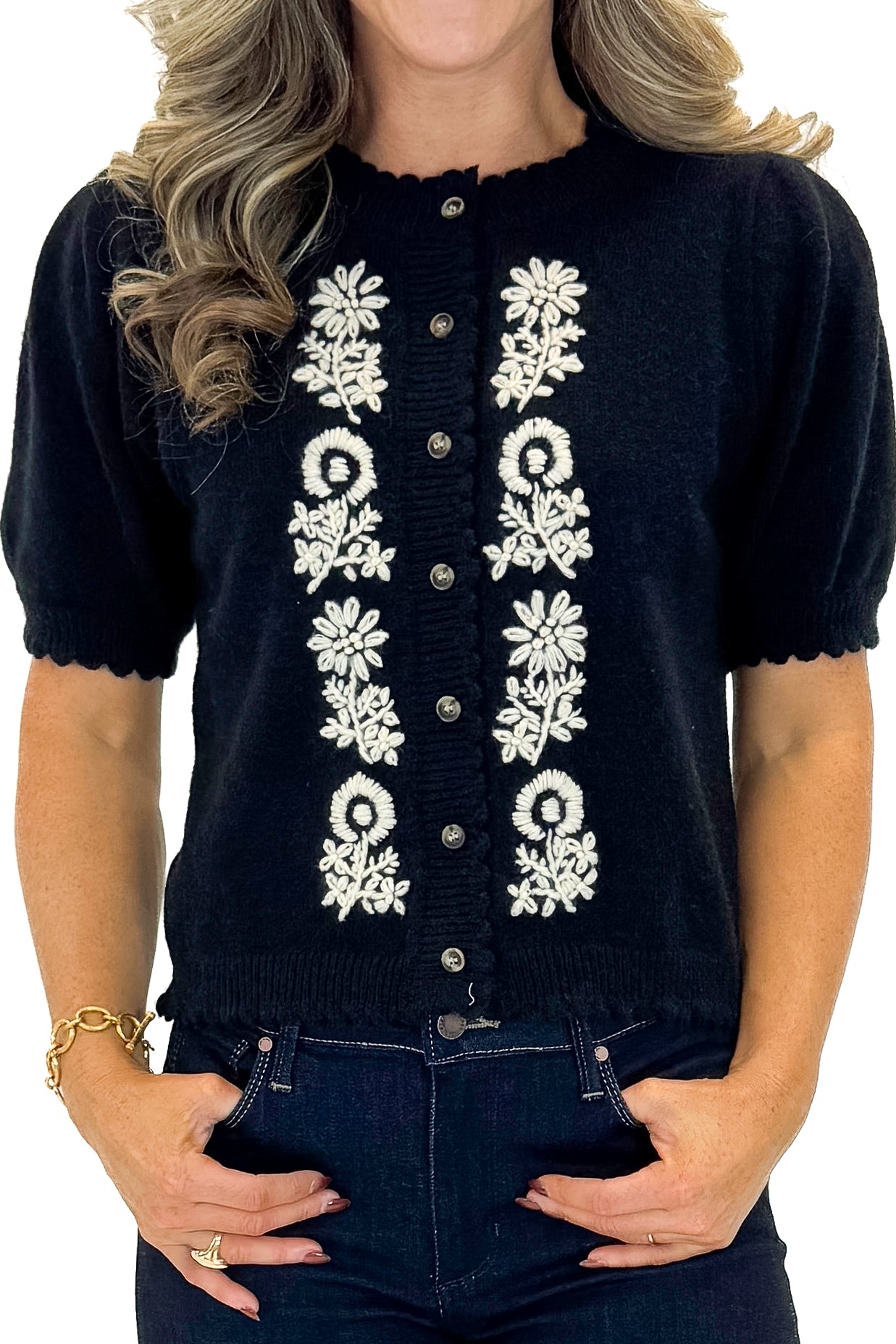 Front detail view of woman wearing Black Center Embroidered Short Sleeve Cardigan with jeans against white studio background.