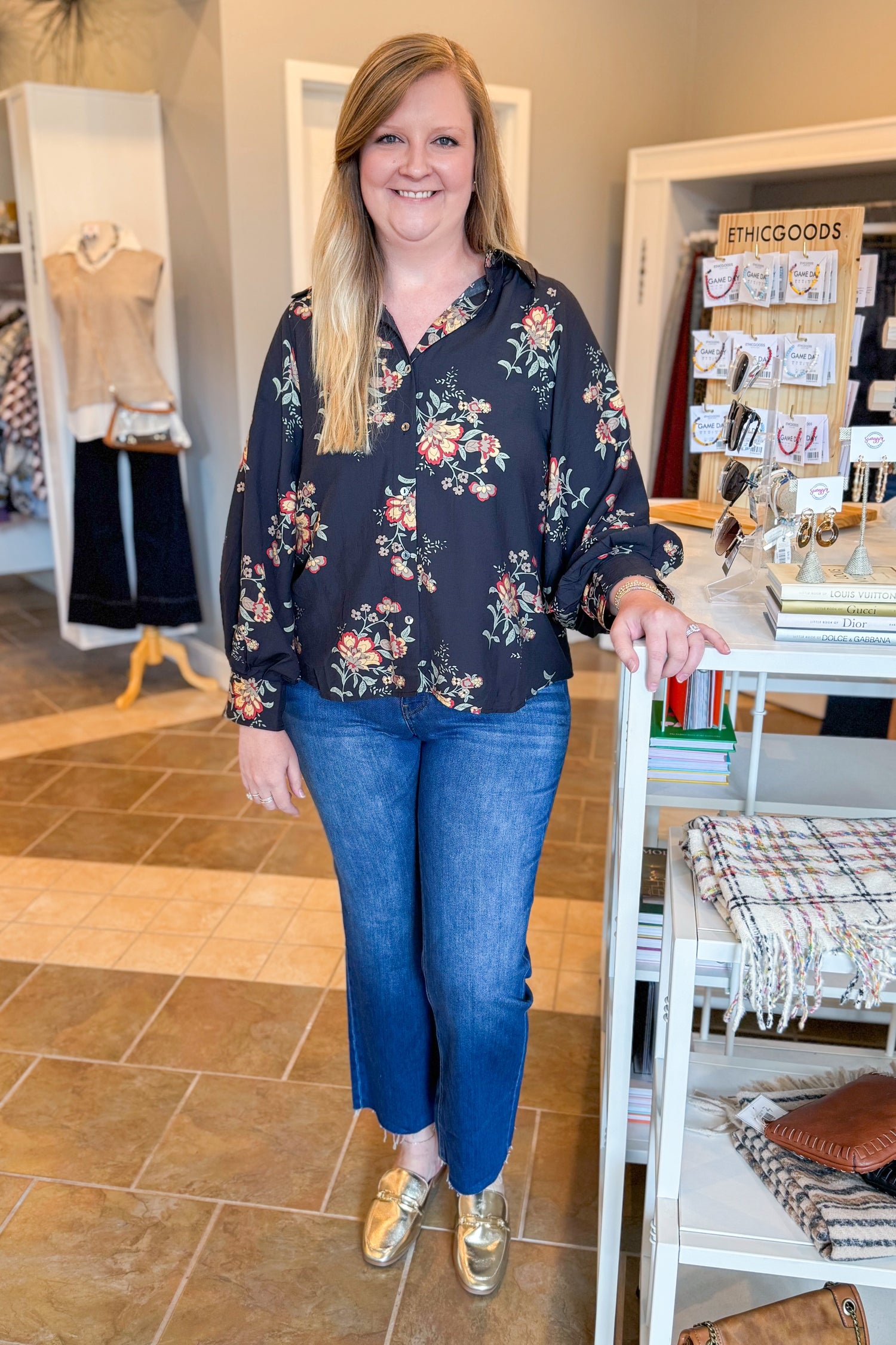Woman wearing a floral blouse and blue jeans standing in a store.