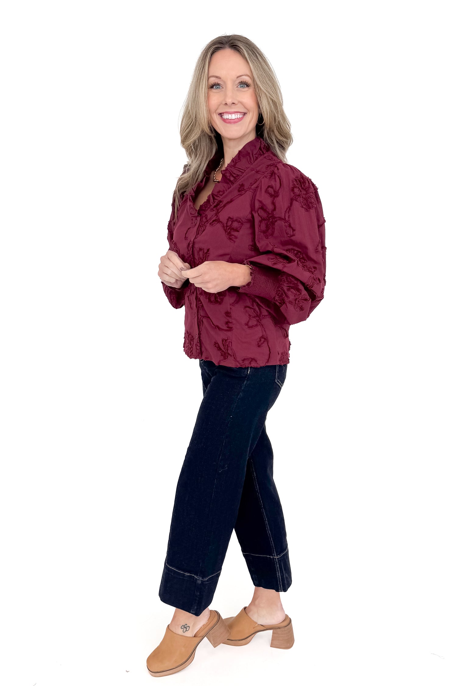Side view of woman wearing button down top with jeans against white studio background.