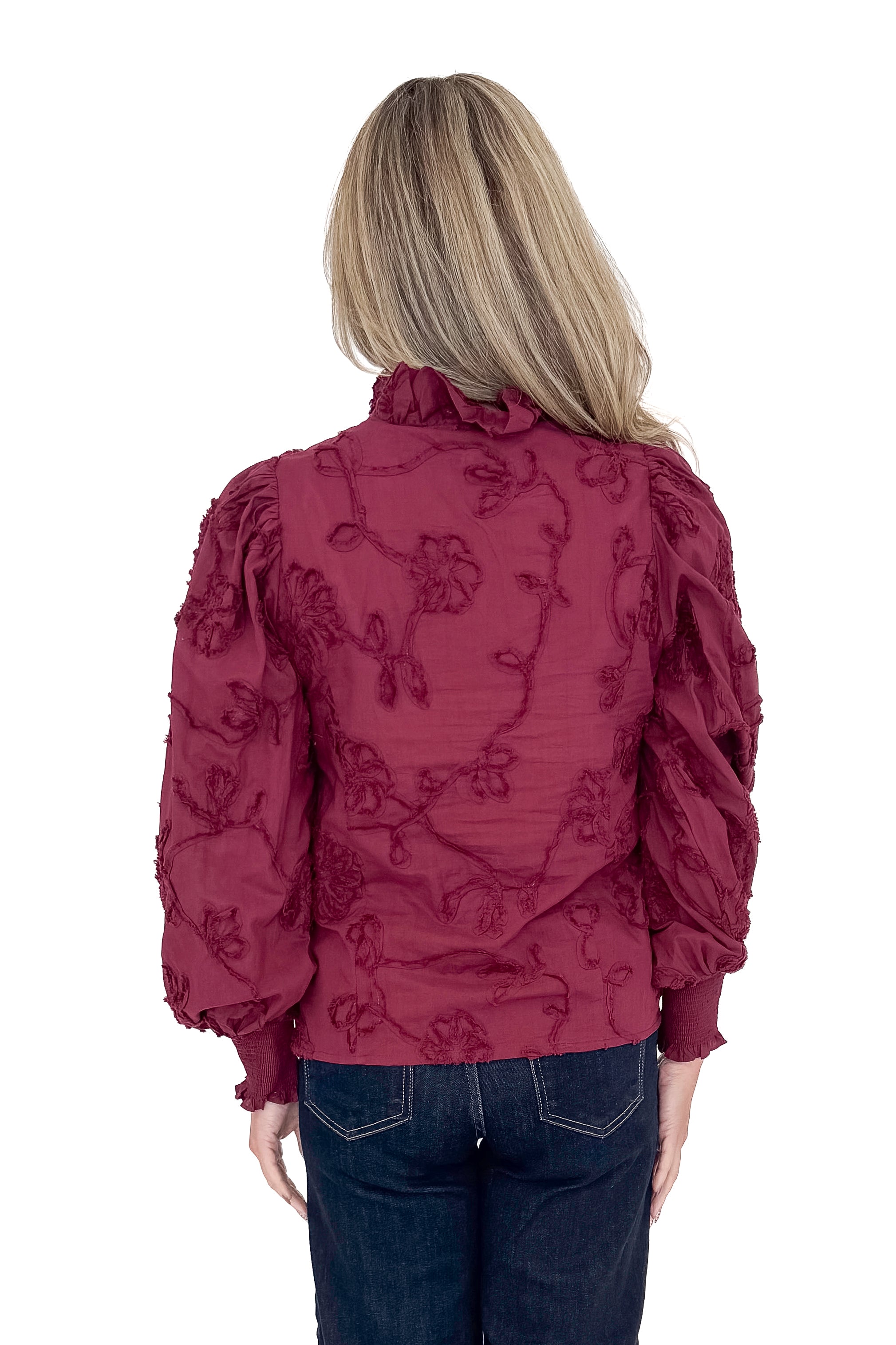 Back view of woman wearing button down top with jeans against white studio background.
