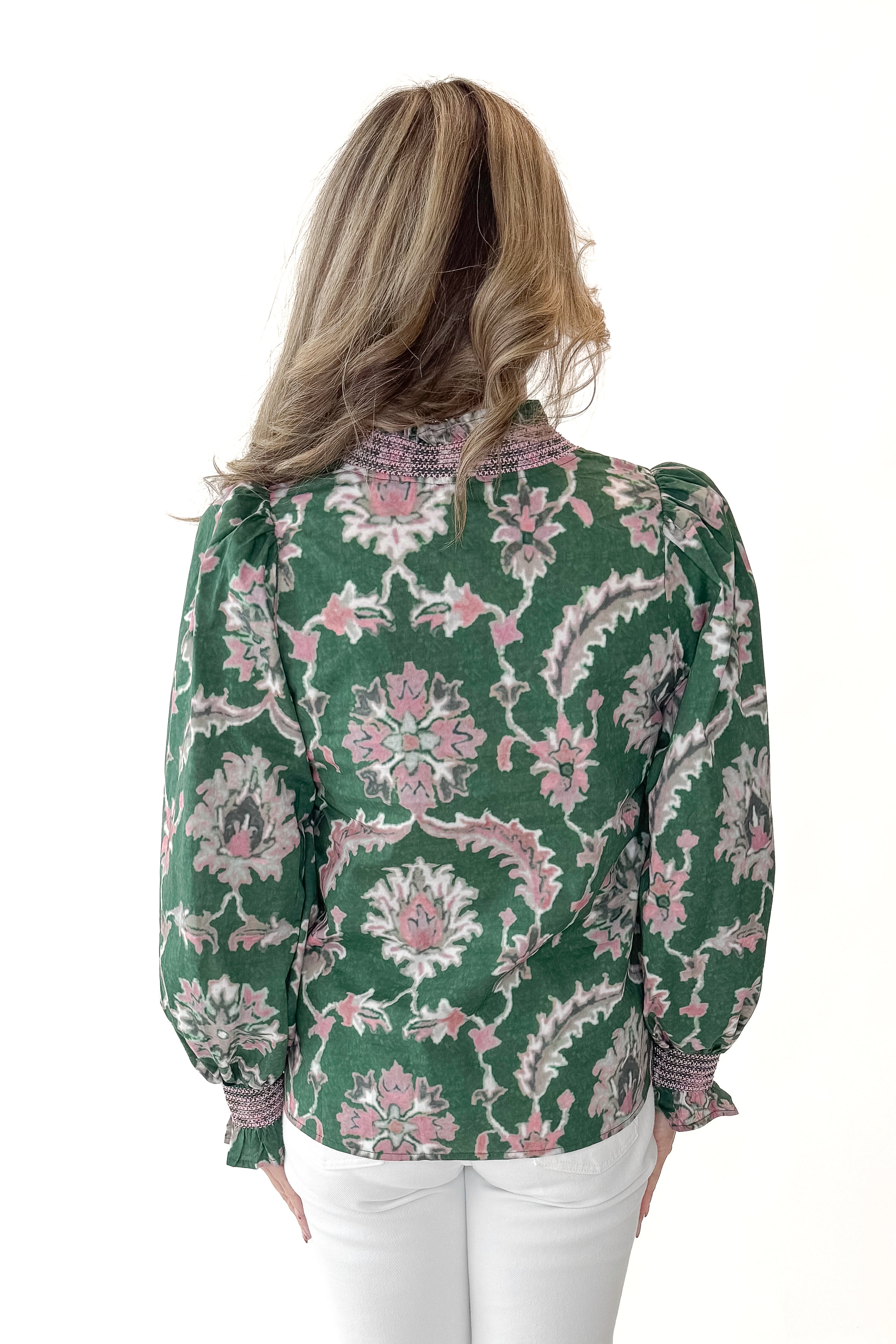 Back view of woman wearing Green & Pink Printed Smocked Center Top with jeans against white studio background.