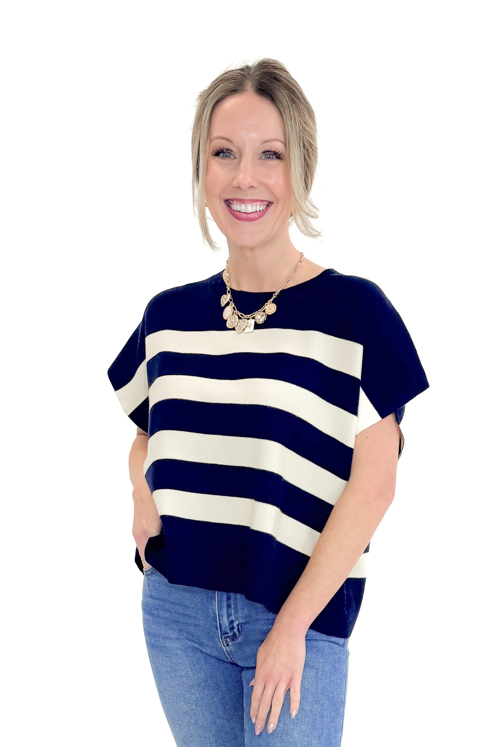Front view of woman wearing Navy & Cream Sleeveless Sweater by Entro with jeans against white studio background.