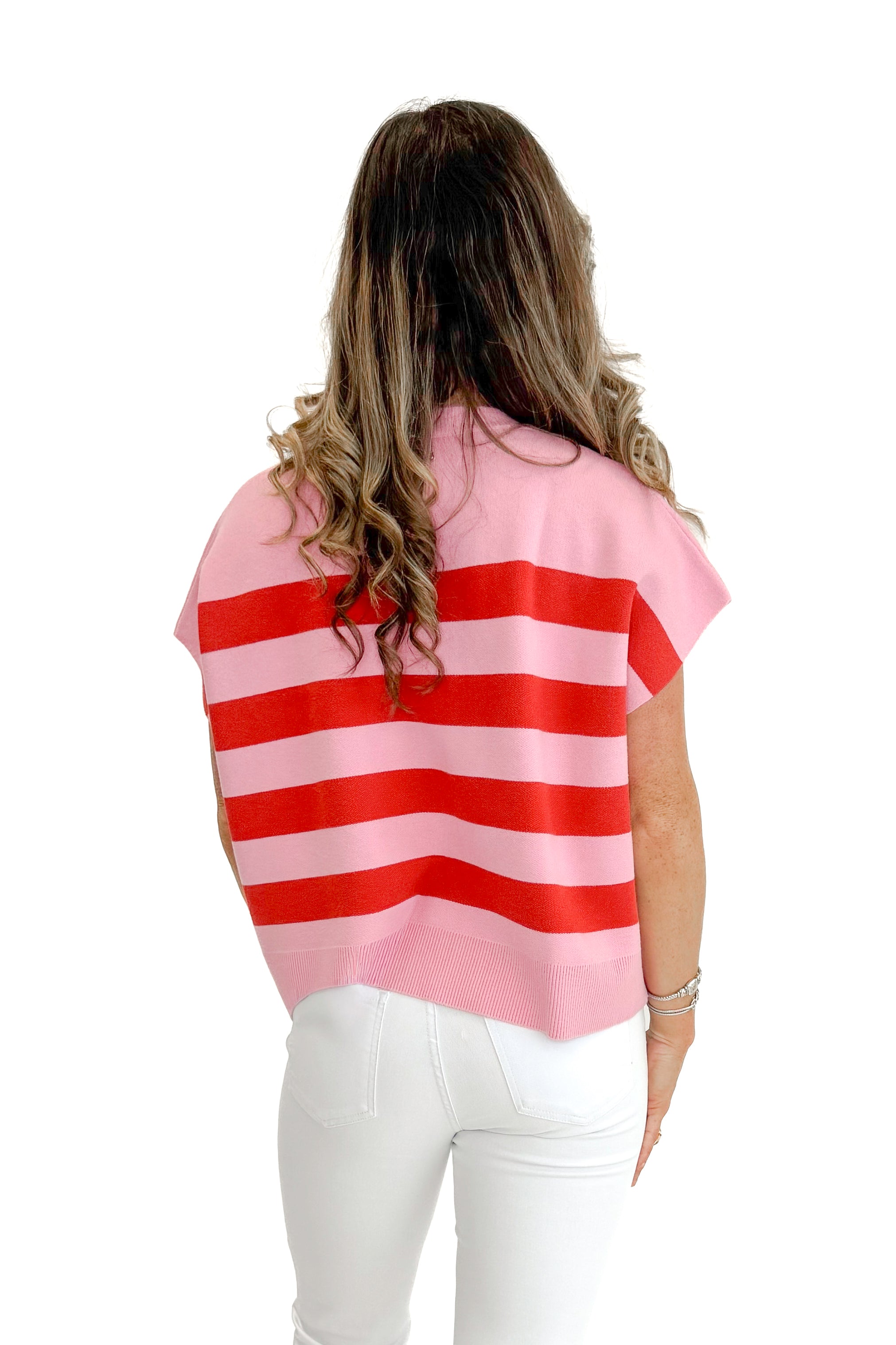 Back view of woman wearing Pink & Red Sleeveless Sweater by Entro with jeans against white studio background.