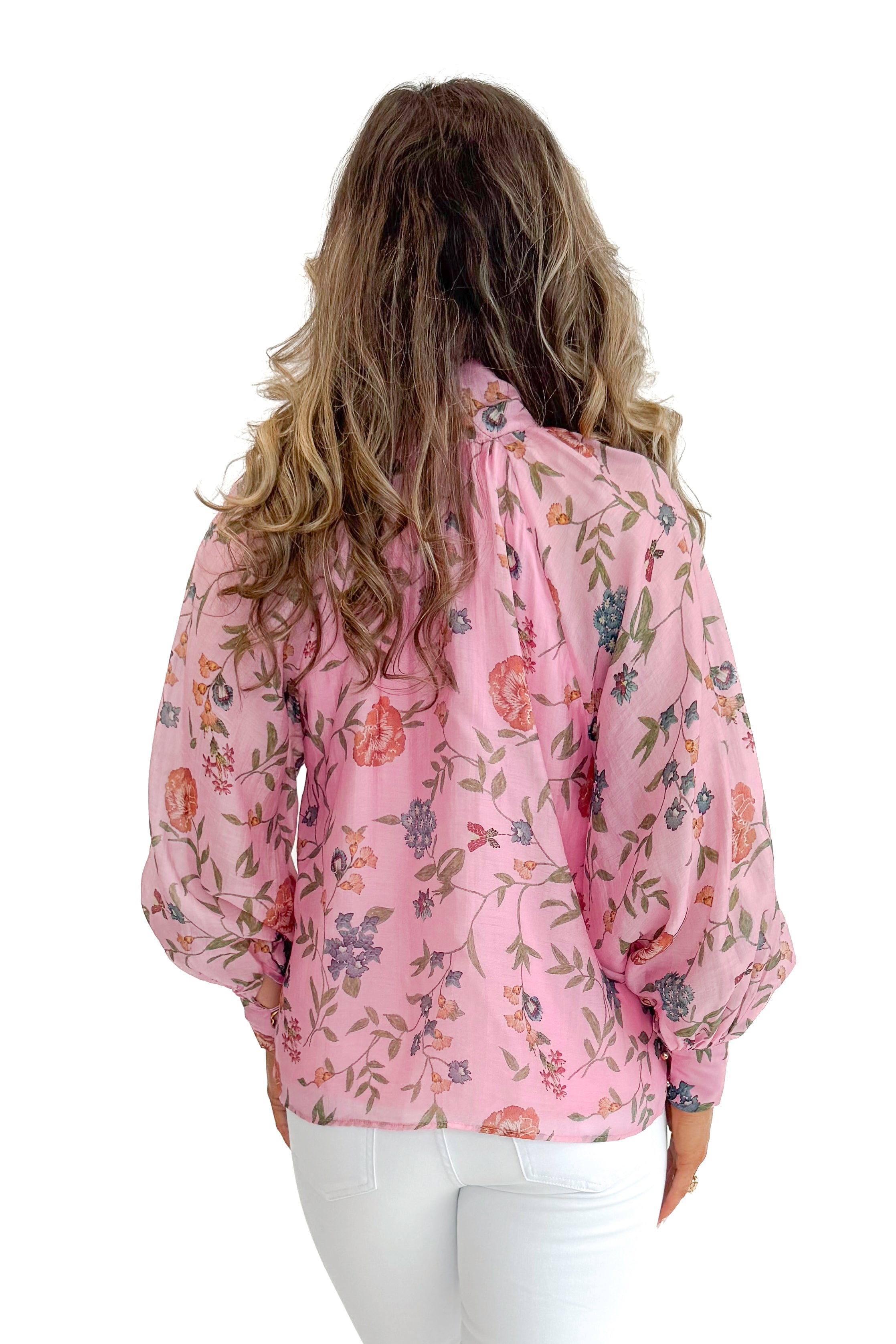 Back view of woman wearing Pink Floral Tie Neck Top by Entro with jeans against white studio background.