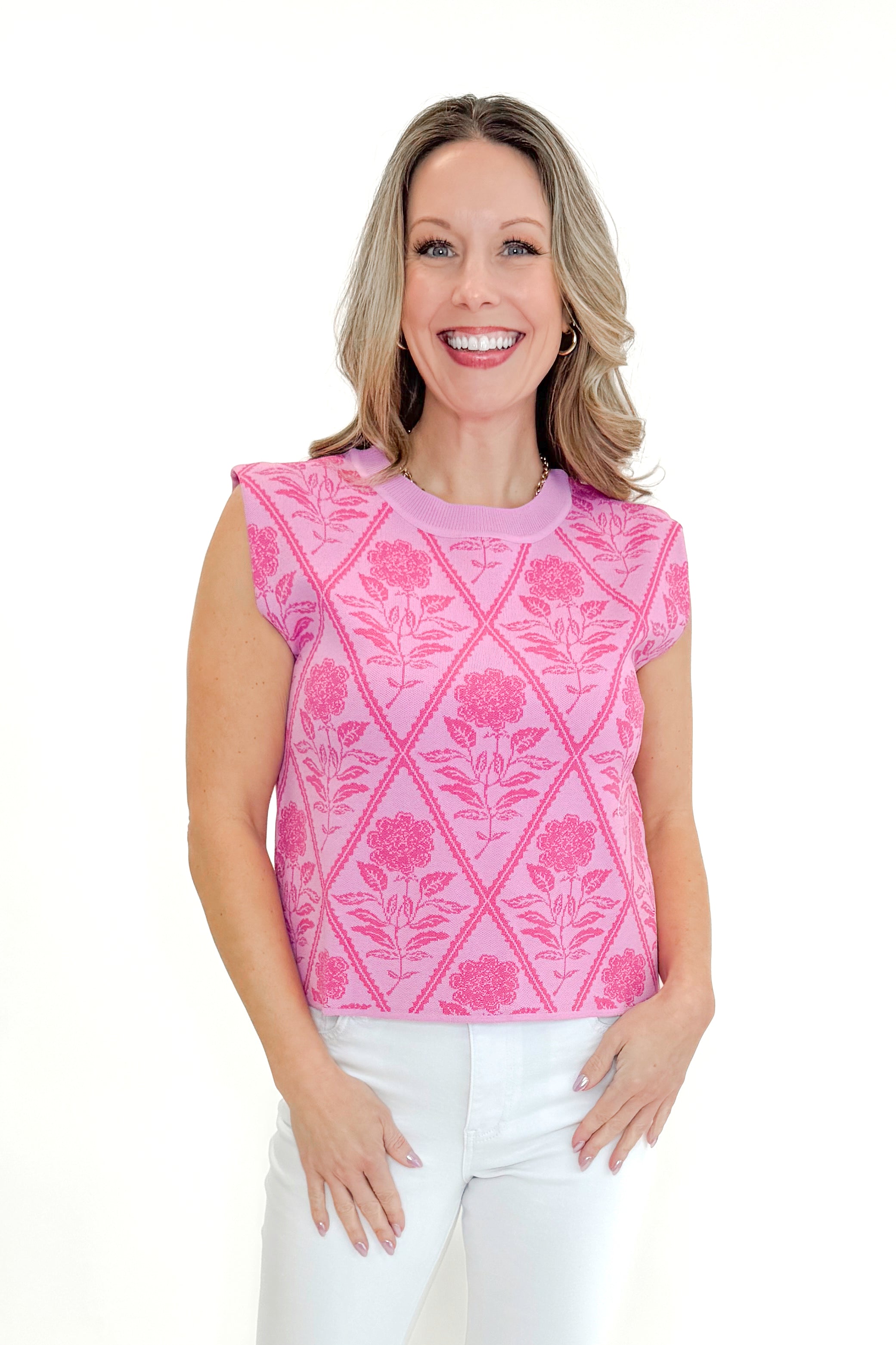 Front view of woman wearing Pink Floral Printed Sleeveless Sweater by Entro with jeans against white studio background.