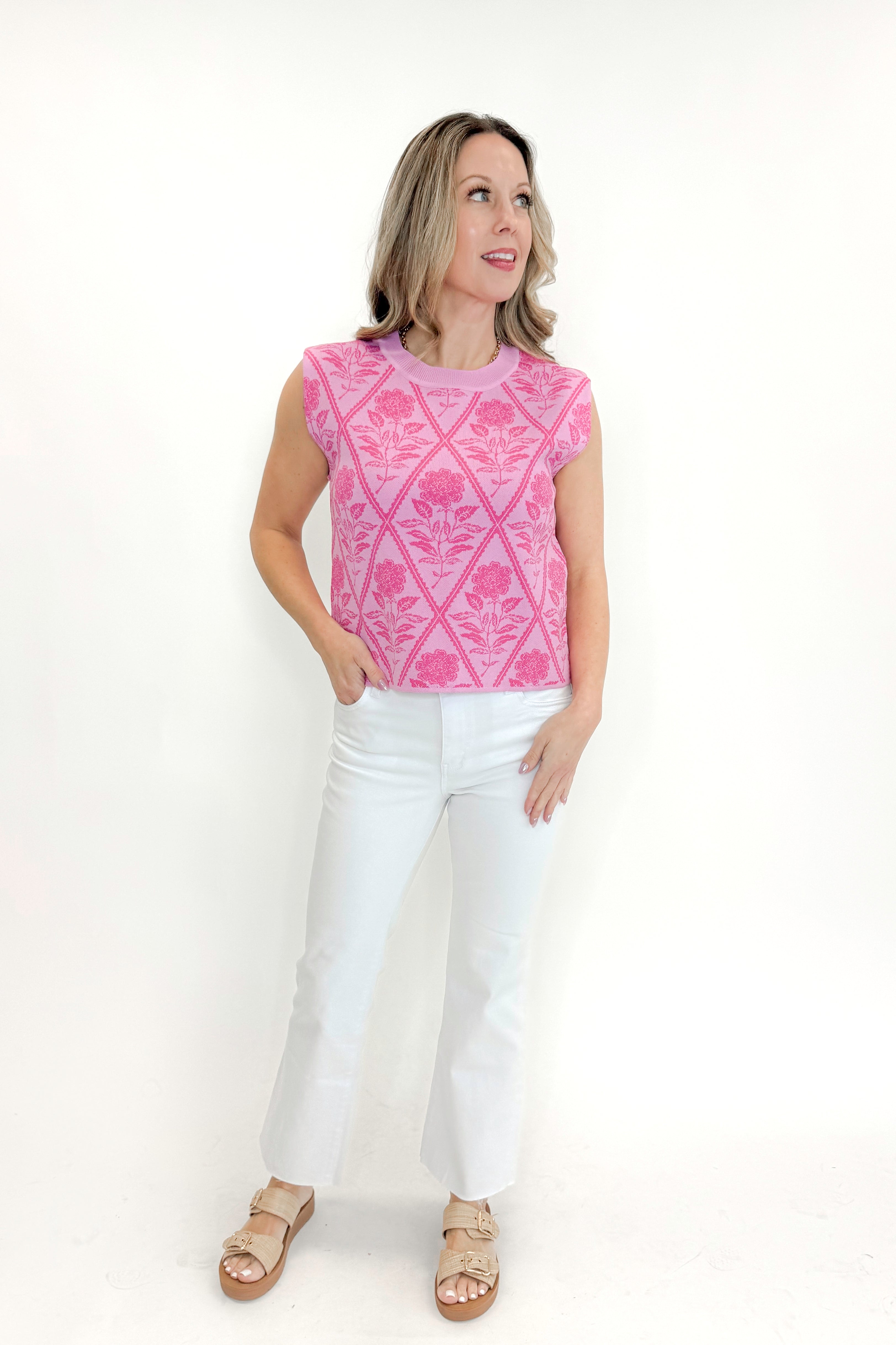Front view of woman wearing Pink Floral Printed Sleeveless Sweater by Entro with jeans against white studio background.