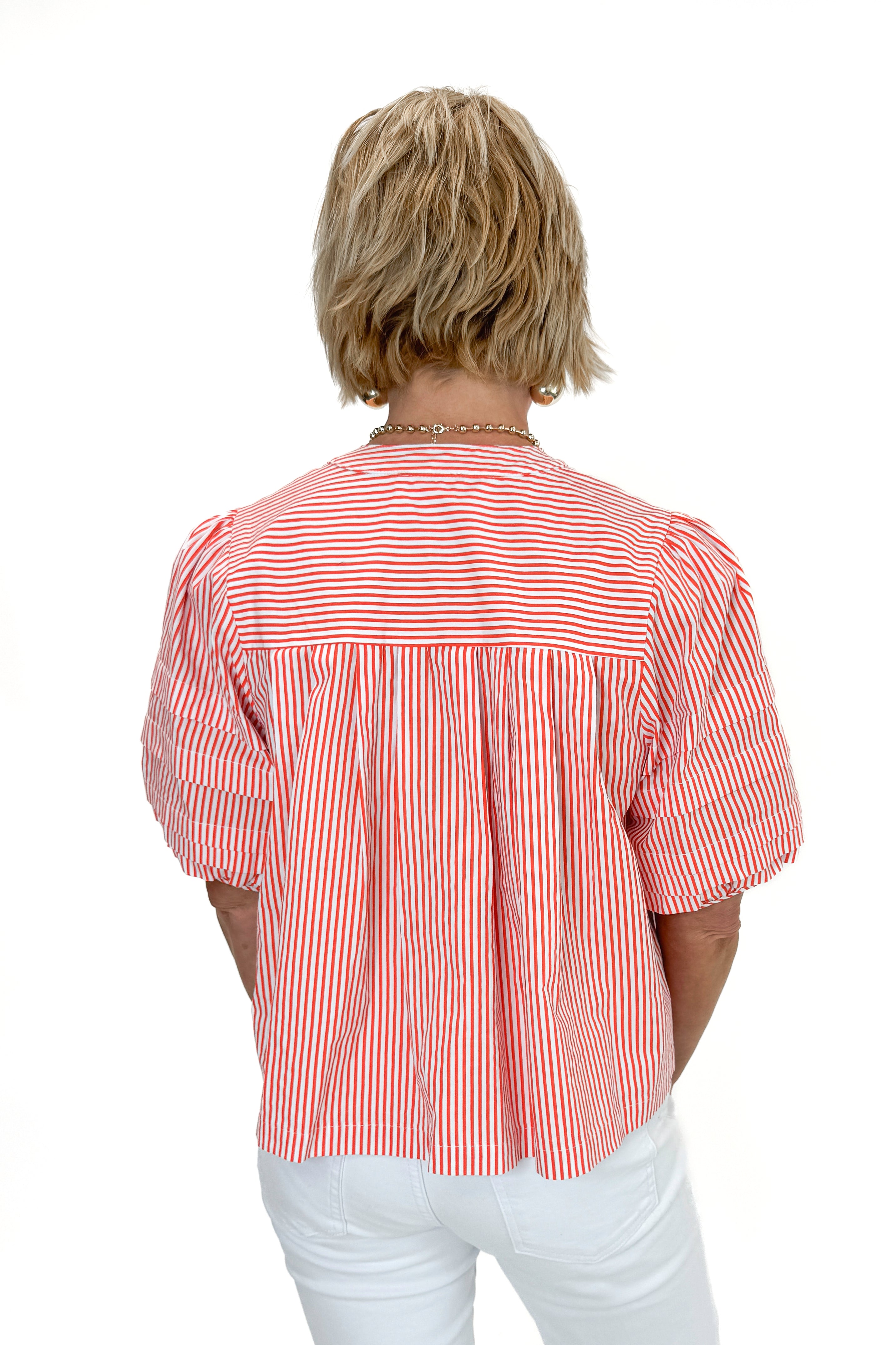 Back view of woman wearing Orange Striped Puff Sleeve Top by Entro with jeans against white studio background.