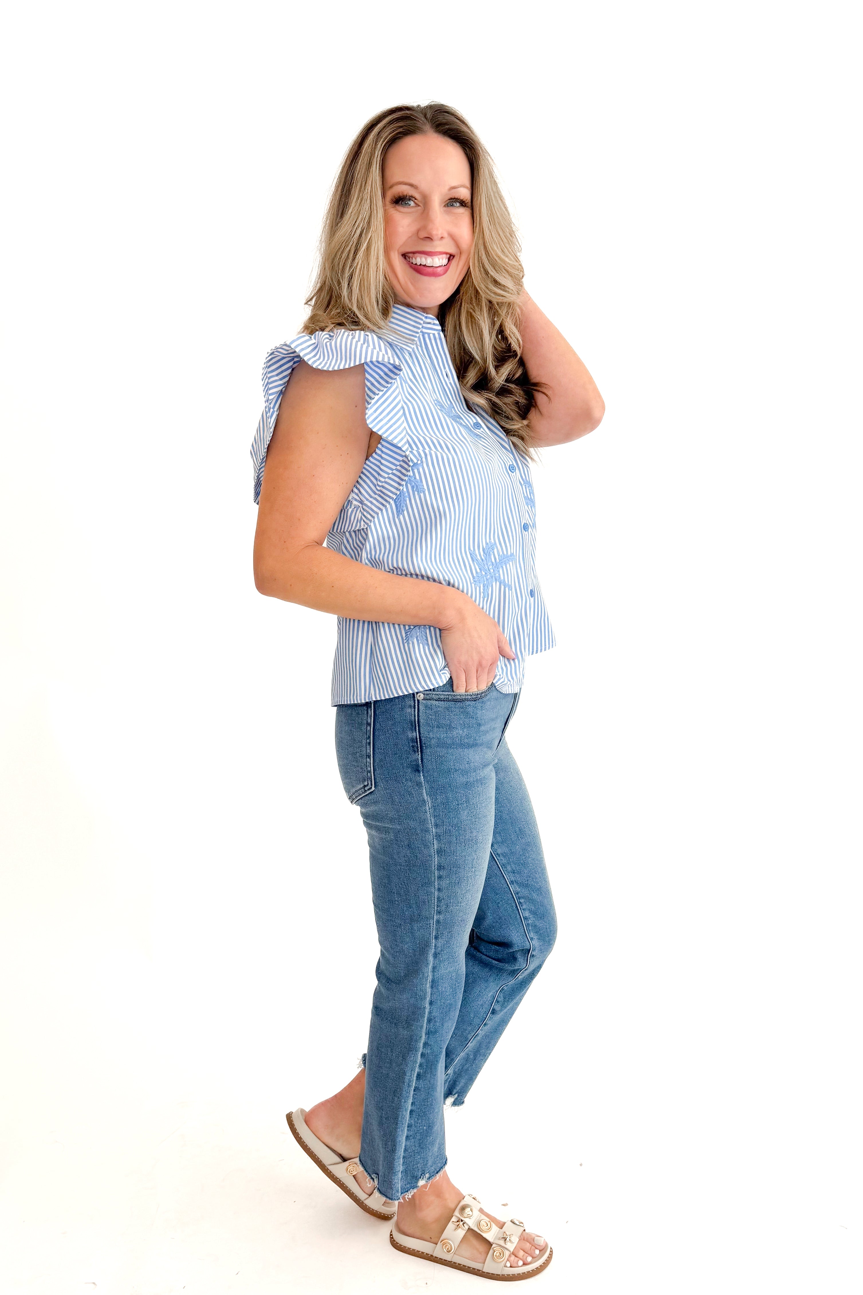 Side view of woman wearing Blue Striped Embroidered Top by Entro with jeans against white studio background.