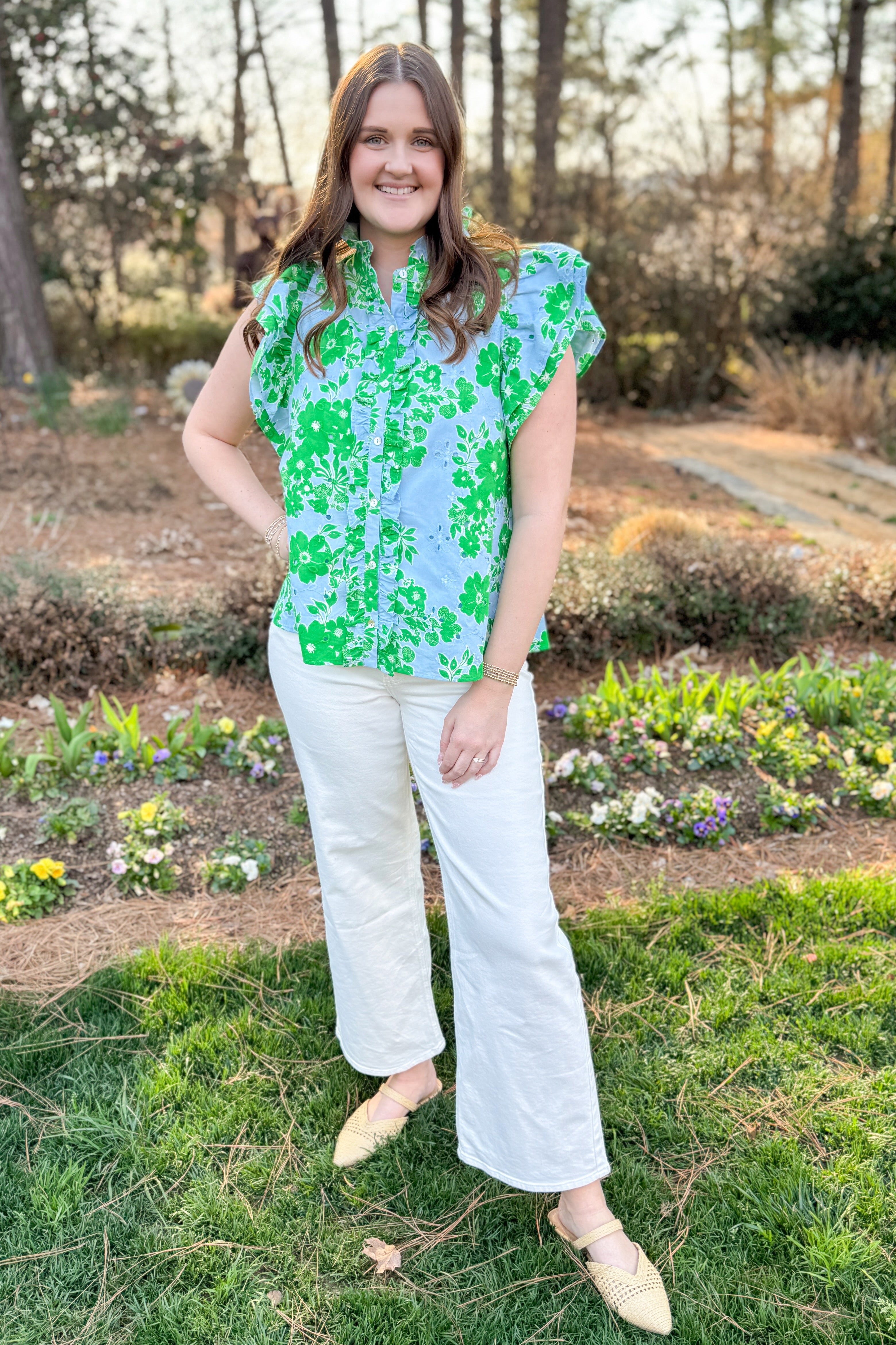 Front view of woman wearing Green & Blue Floral Eyelet Top by Entro with white jeans outside at a garden.
