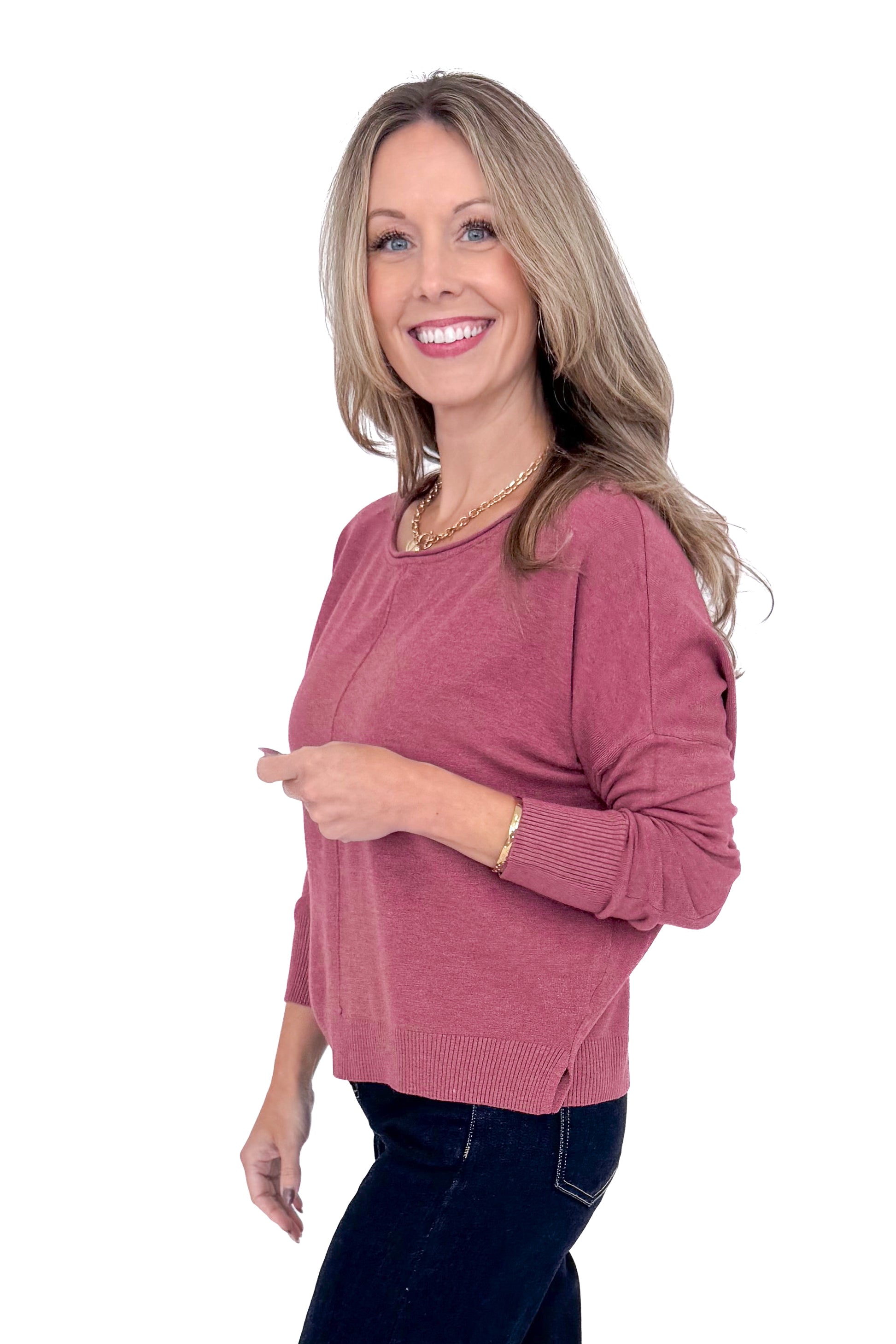 Side view of woman wearing Heathered Berry Center Seam Sweater and blue jeans.