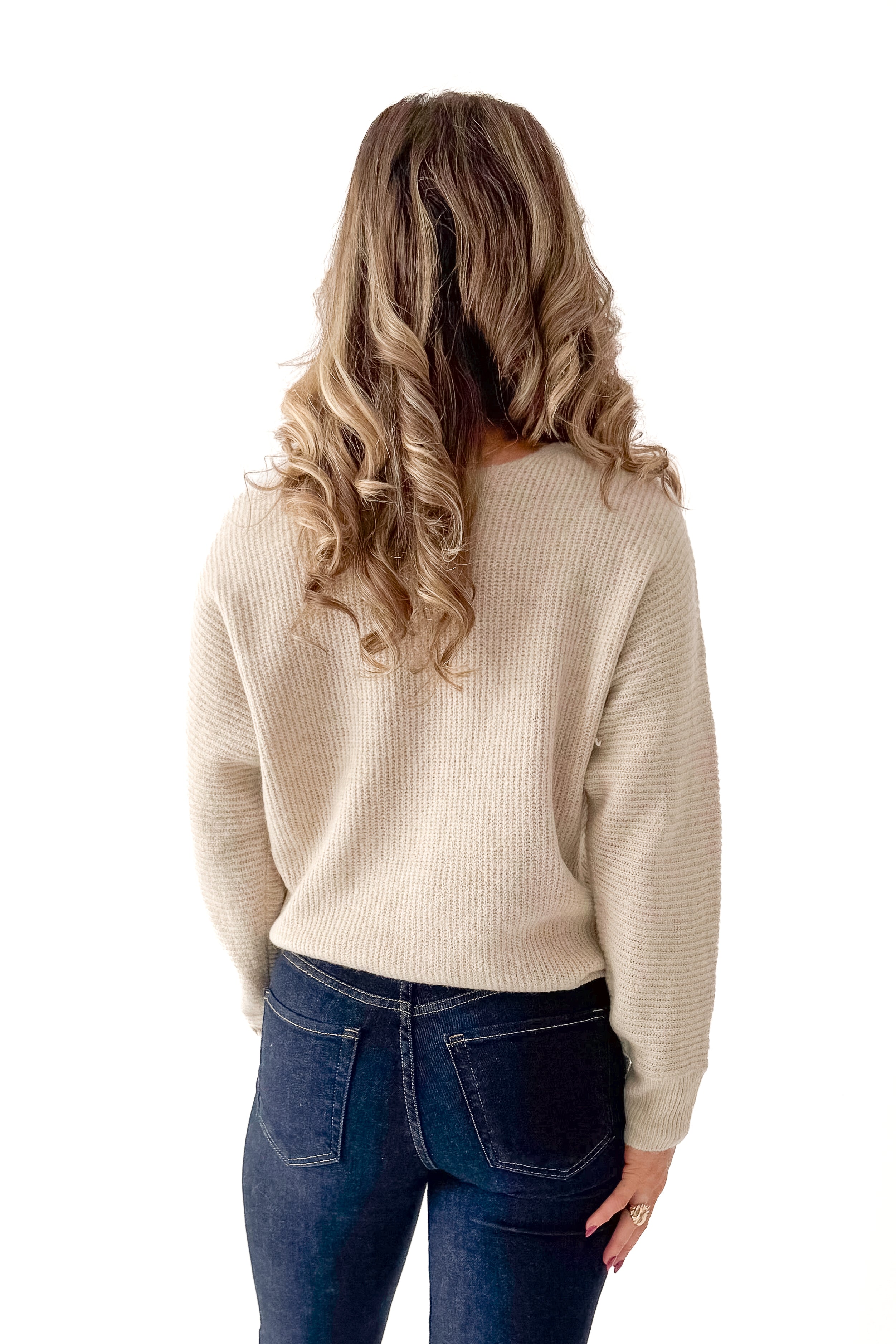 Back view of woman wearing Almond V-neck Sweater with jeans against white studio background.