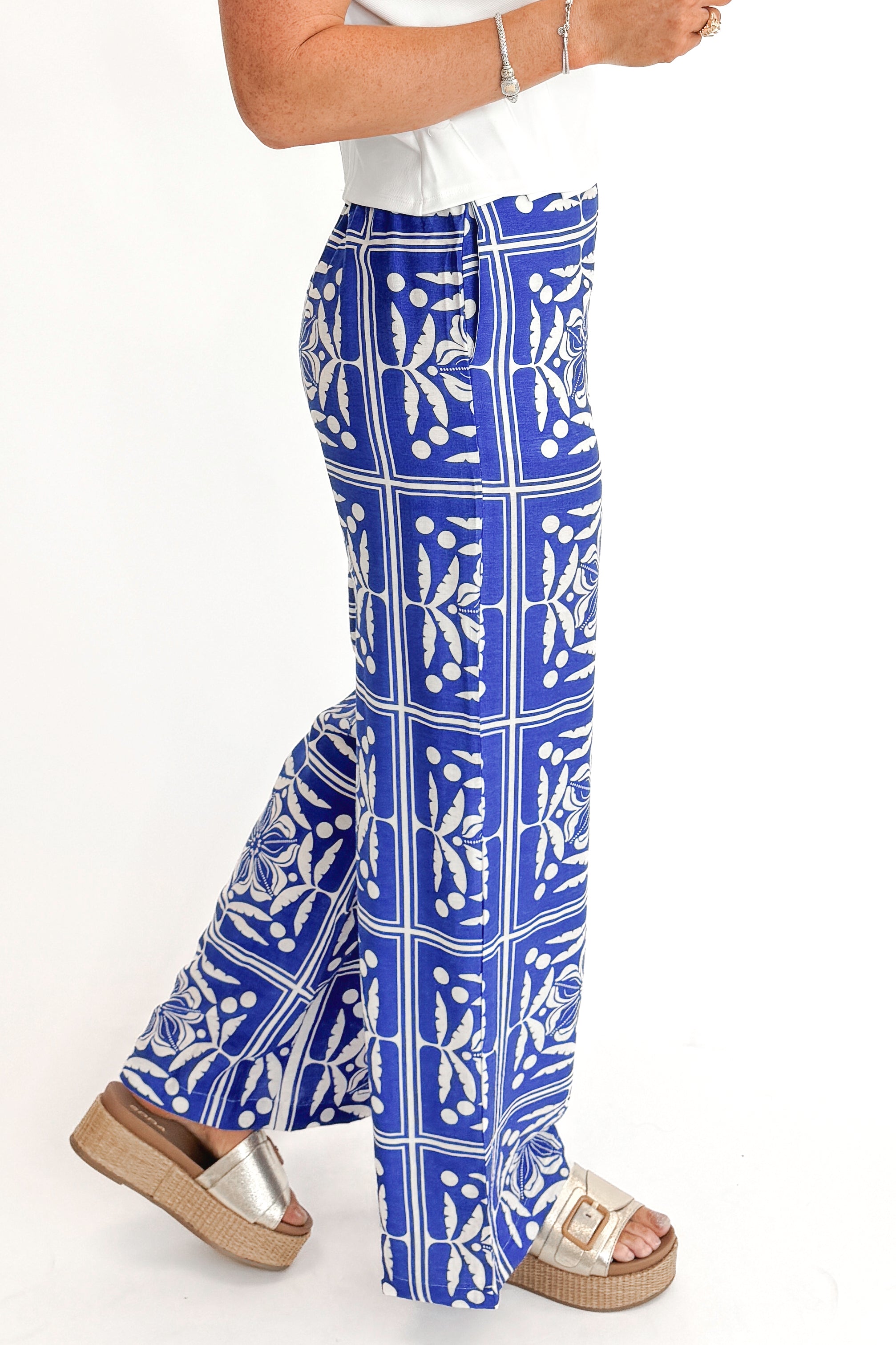 Side view of woman wearing Blue Floral Print Wide Leg Pants with top against white studio background.
