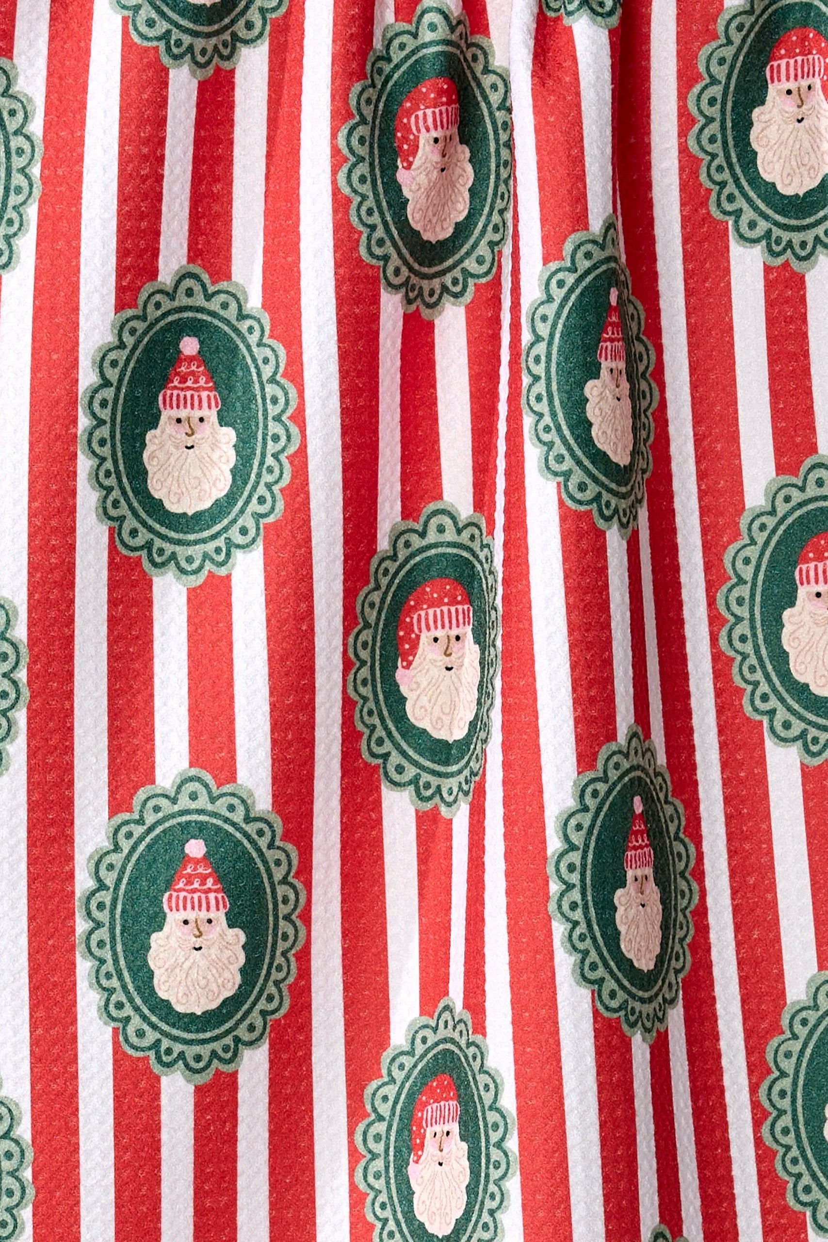 Pattern of Santa Claus faces in green frames on red and white striped background