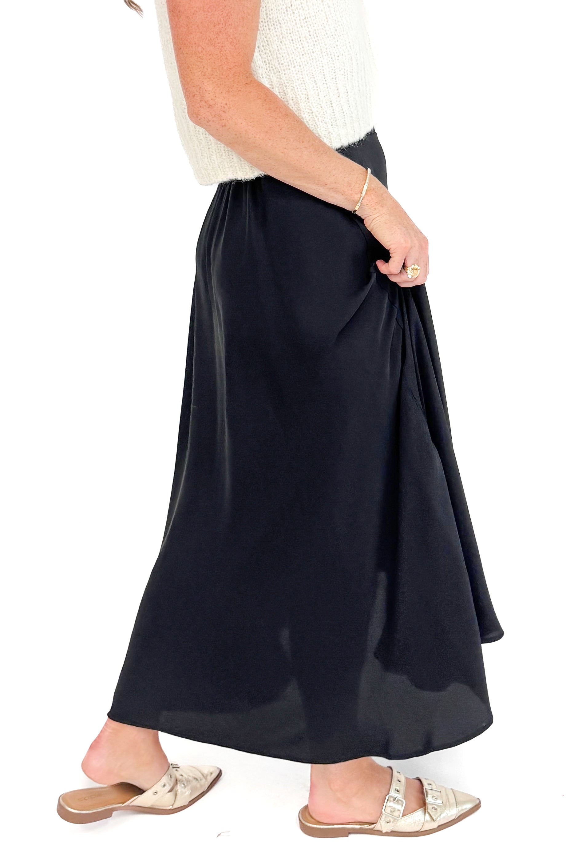 Side close up view of black satin swing skirt showing pleated detail.