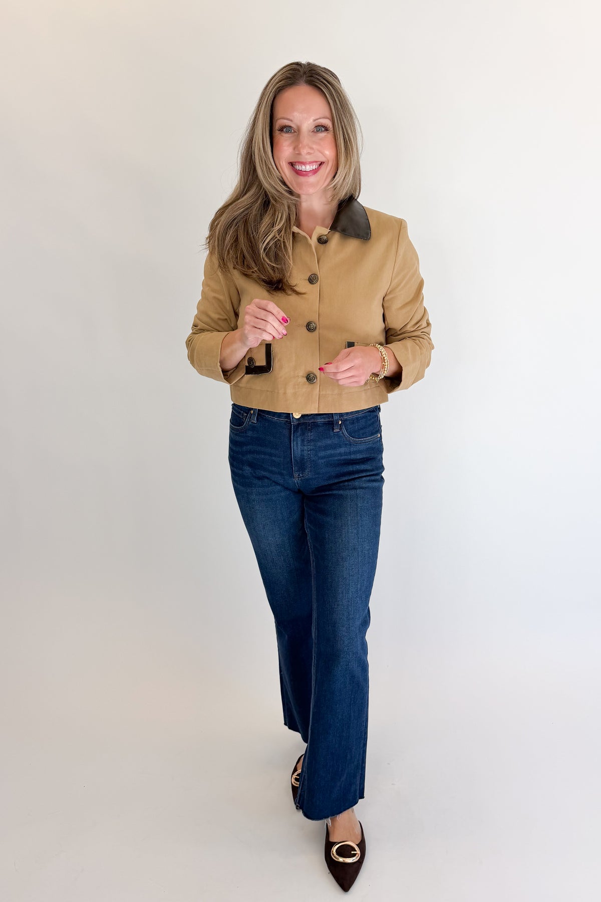 Front view of woman wearing Swagger Boutique’s Taupe Button Up Leather Collared Jacket with jeans against white studio background.