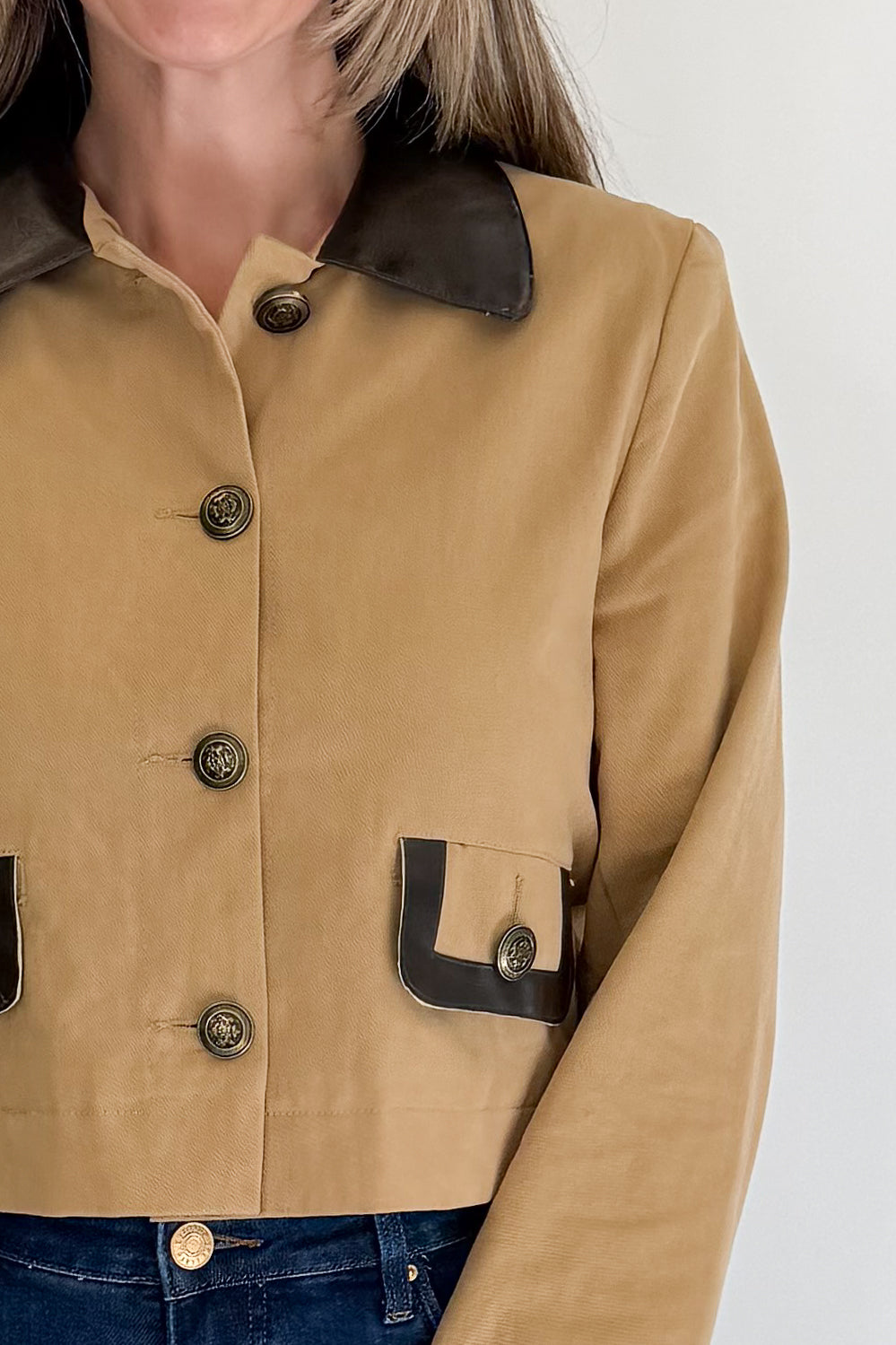 Front detail view of woman wearing Swagger Boutique’s Taupe Button Up Leather Collared Jacket with jeans against white studio background.