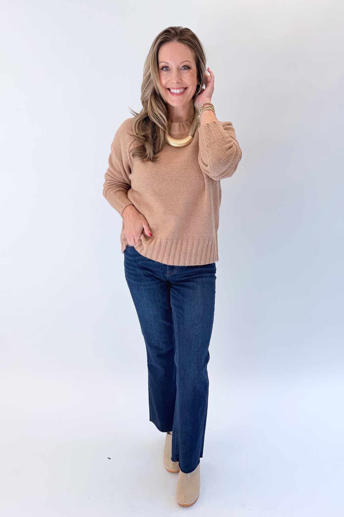 Front view of woman wearing Swagger Boutique’s Taupe Ribbed Hem Sweater with jeans against white studio background.