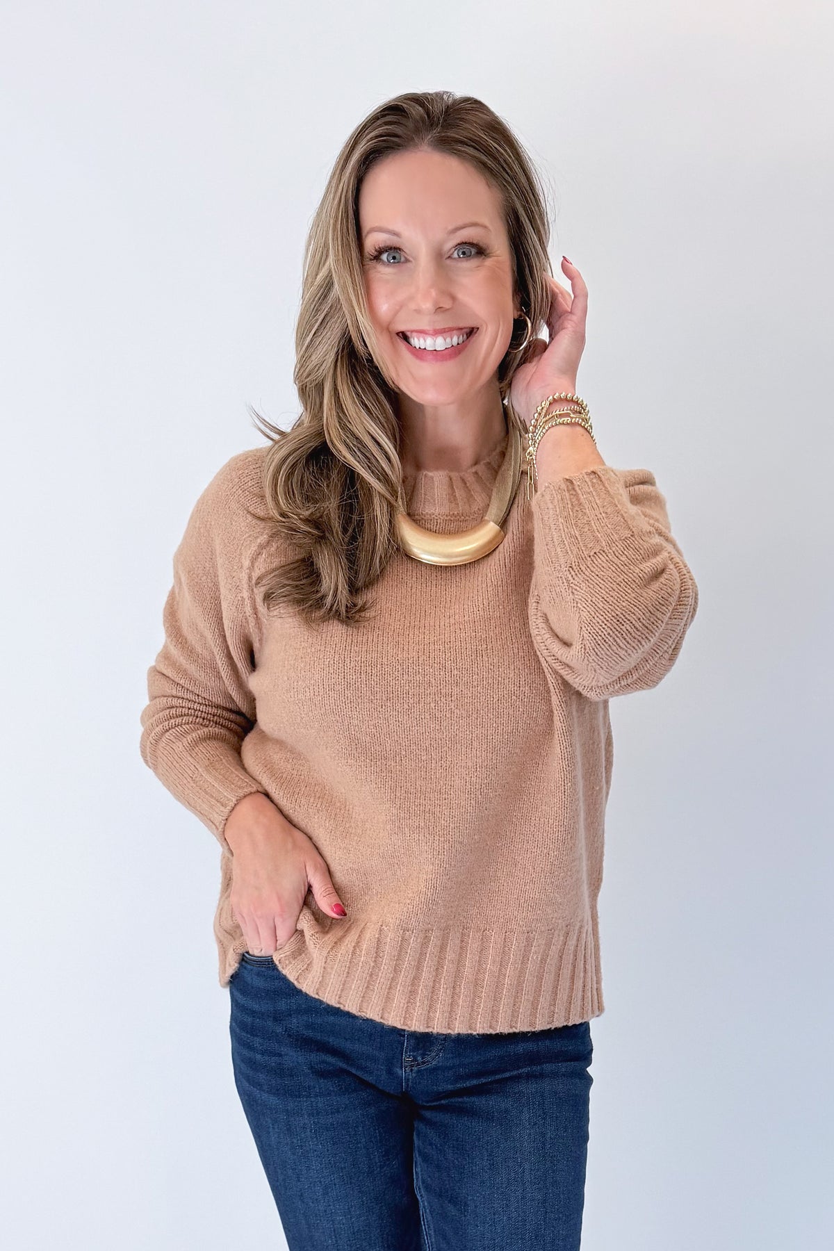 Front view of woman wearing Swagger Boutique’s Taupe Ribbed Hem Sweater with jeans against white studio background.