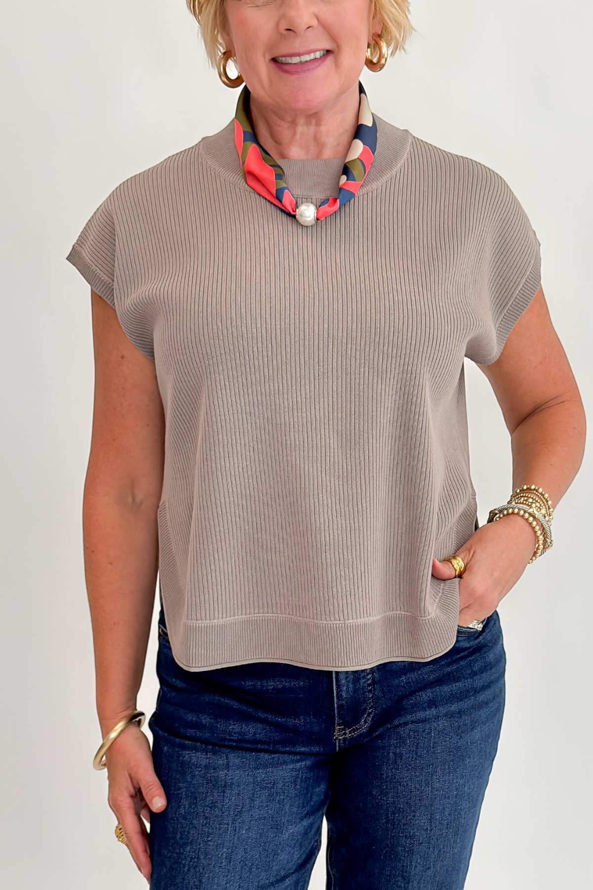 Front detail view of woman wearing Swagger Boutique’s Taupe Ribbed Short Sleeve Sweater by Entro with jeans against white studio background.