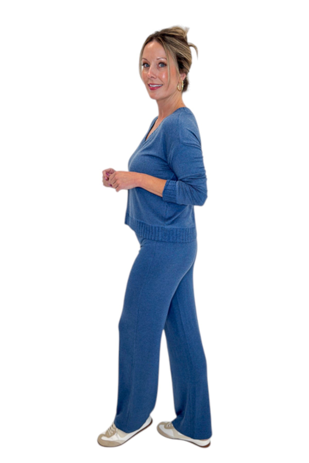 Side view of woman wearing Swagger Boutique’s True Navy Courtney Long Sleeve Top by Z Supply with True Navy Dawn Smocked Pants by Z Supply against white studio background.