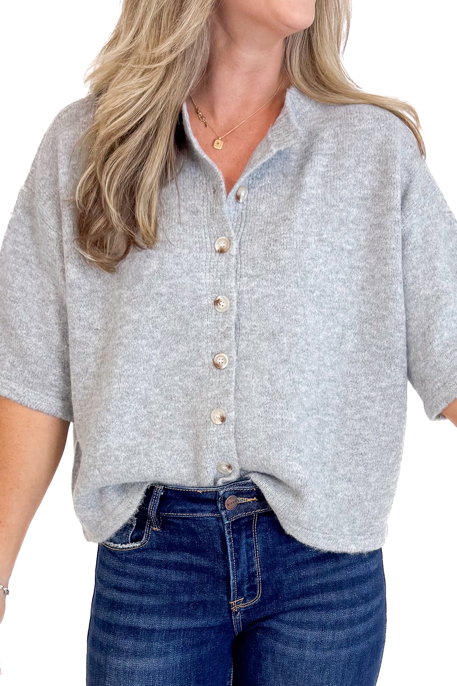 Person wearing a gray button-up shirt and blue jeans on a white background