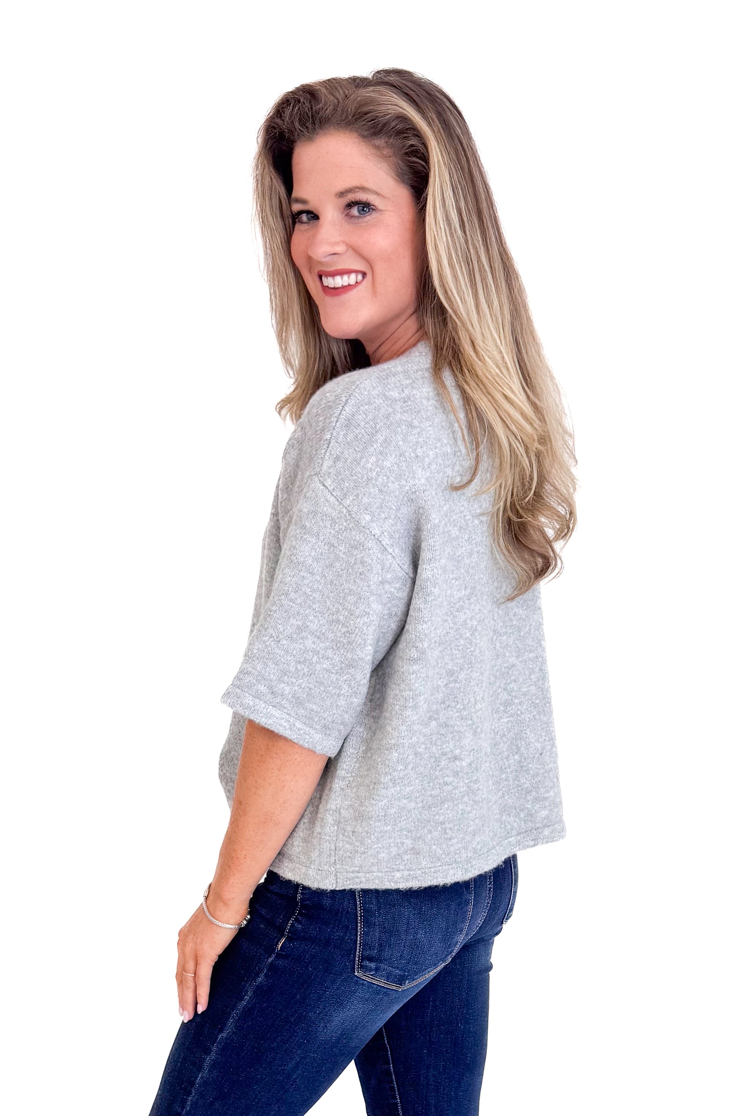 Woman wearing a gray sweater and blue jeans on a white background