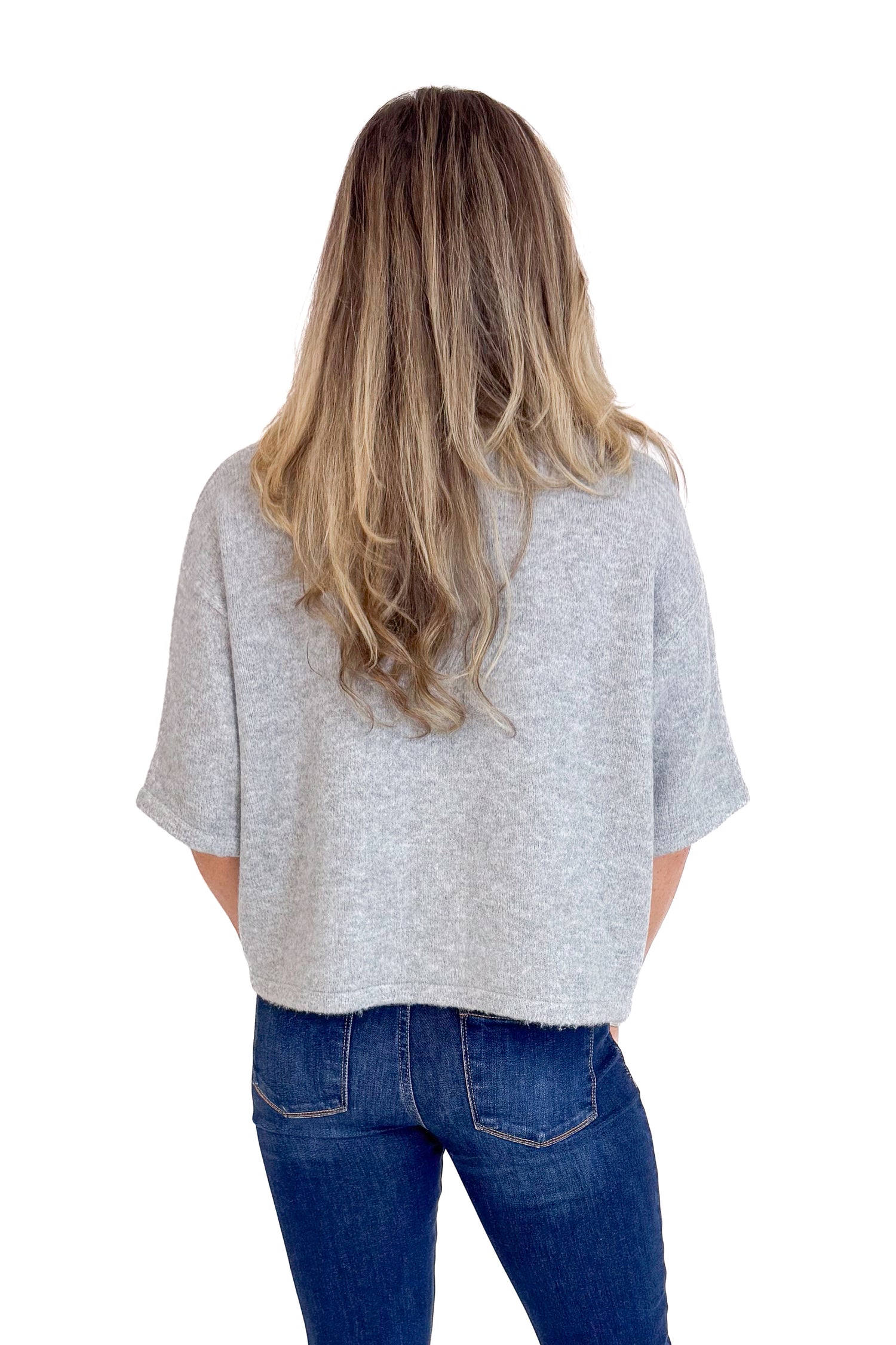 Person wearing a gray t-shirt and blue jeans on a white background