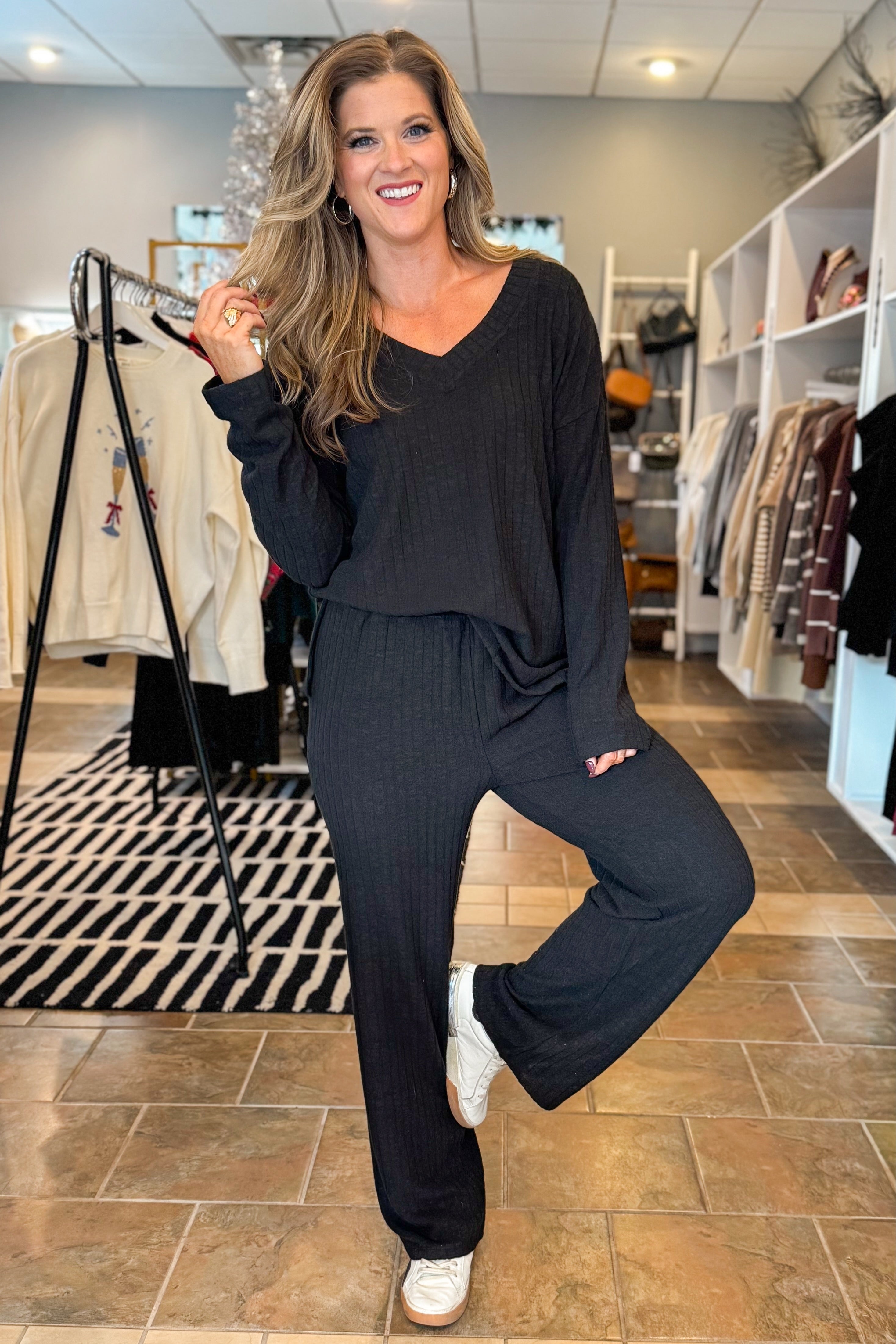 Front view of woman wearing Black Ribbed V-neck Long Sleeve Top with matching pants against white studio background.