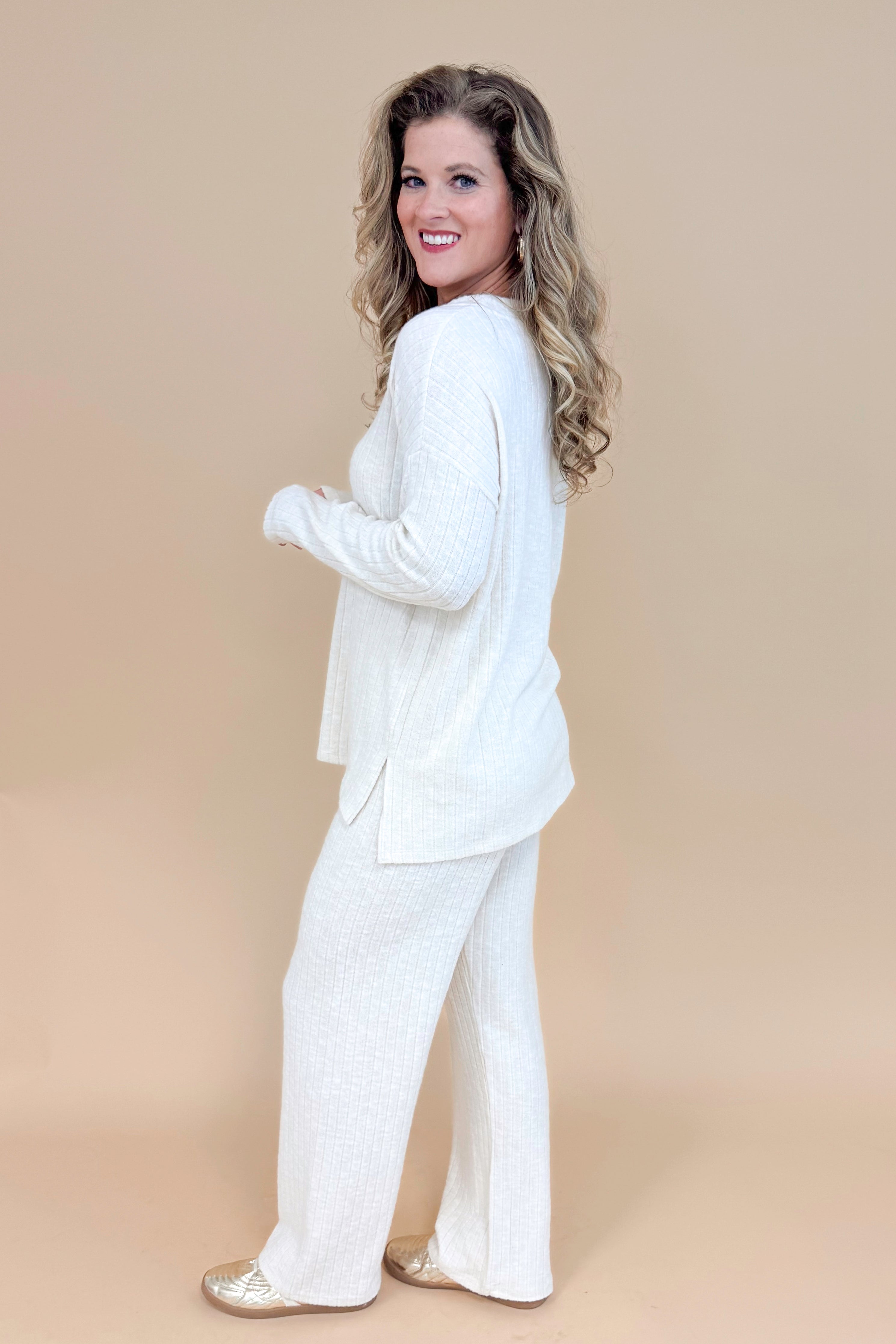 Side view of model wearing cream ribbed lounge pants and matching long sleeve top.