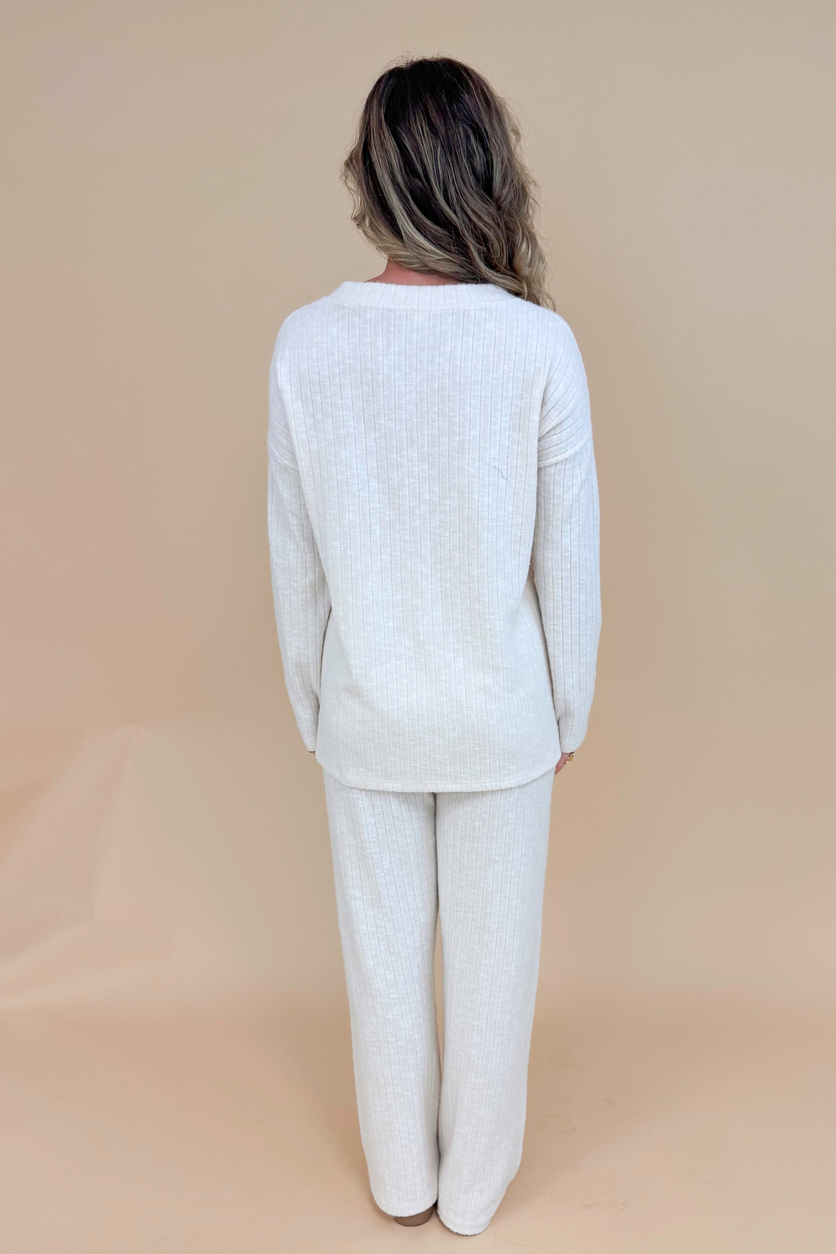 Back view of model wearing cream ribbed lounge pants and matching long sleeve top.