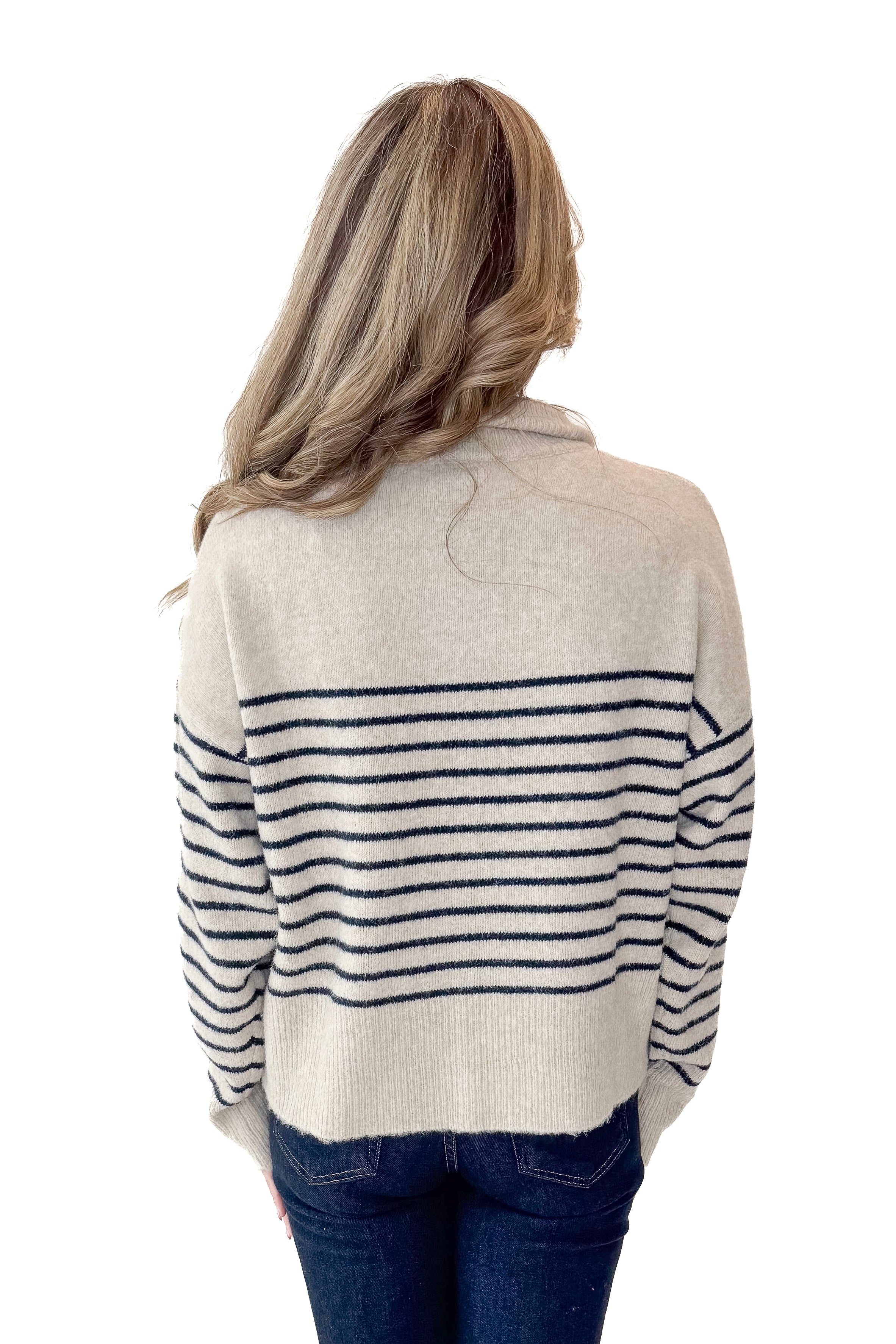 Back view of woman wearing Oatmeal and Navy Striped Button Detail Sweater with jeans against white studio background.