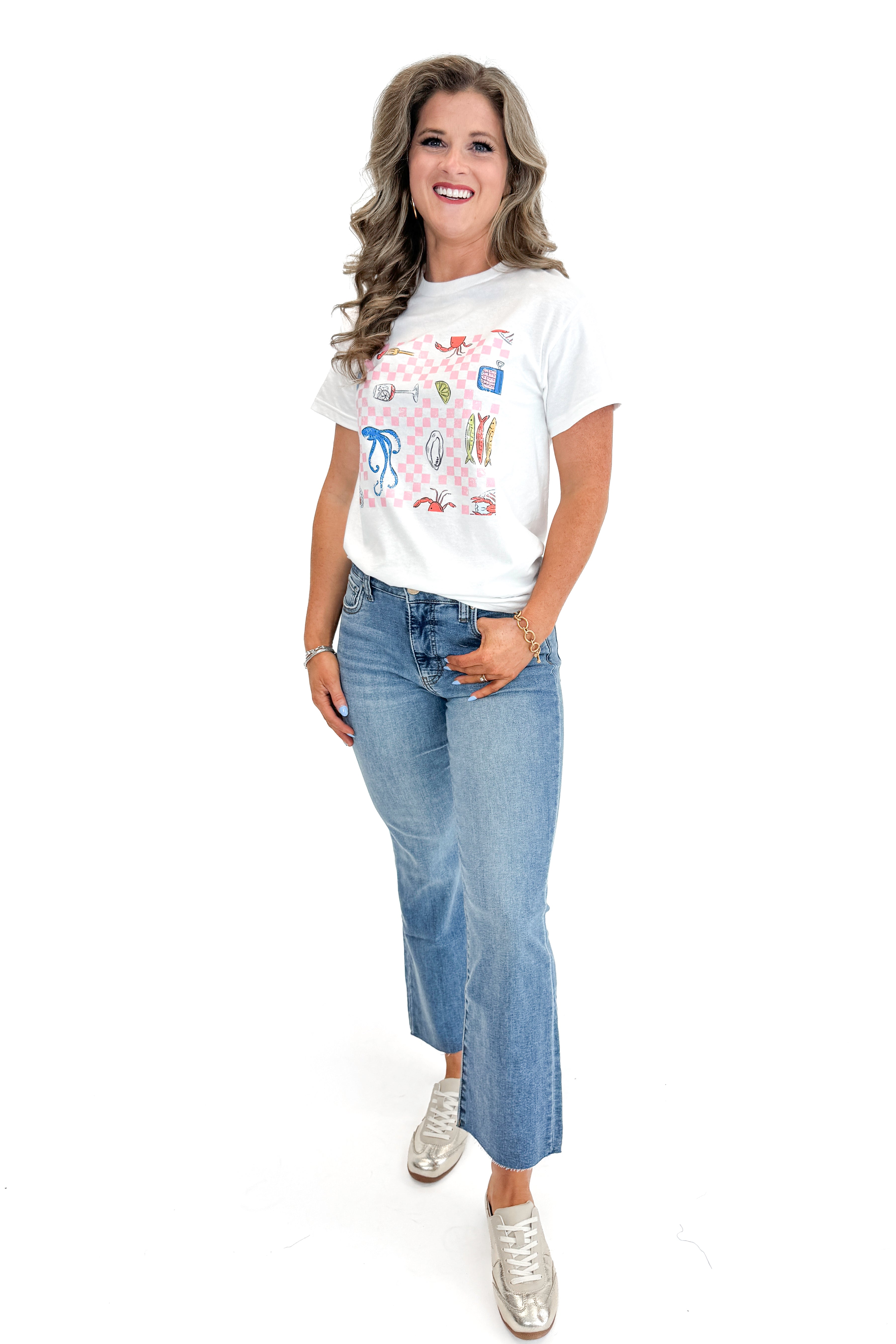 Front view of woman wearing Fish & Checkered Graphic Tee with jeans against white studio background.