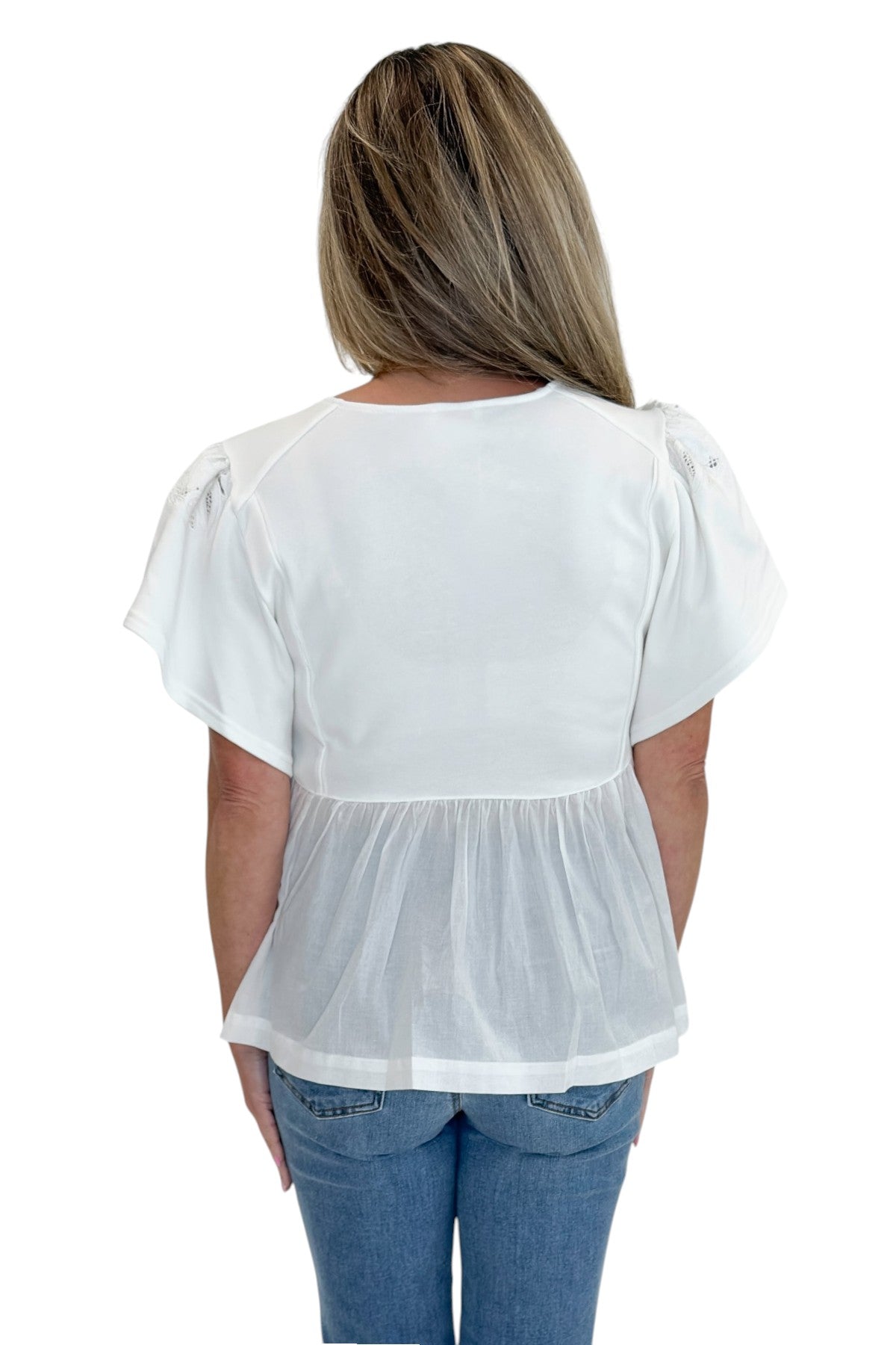 Back view of woman wearing Swagger Boutique’s White Embroidered Peplum Top with jeans against white studio background.