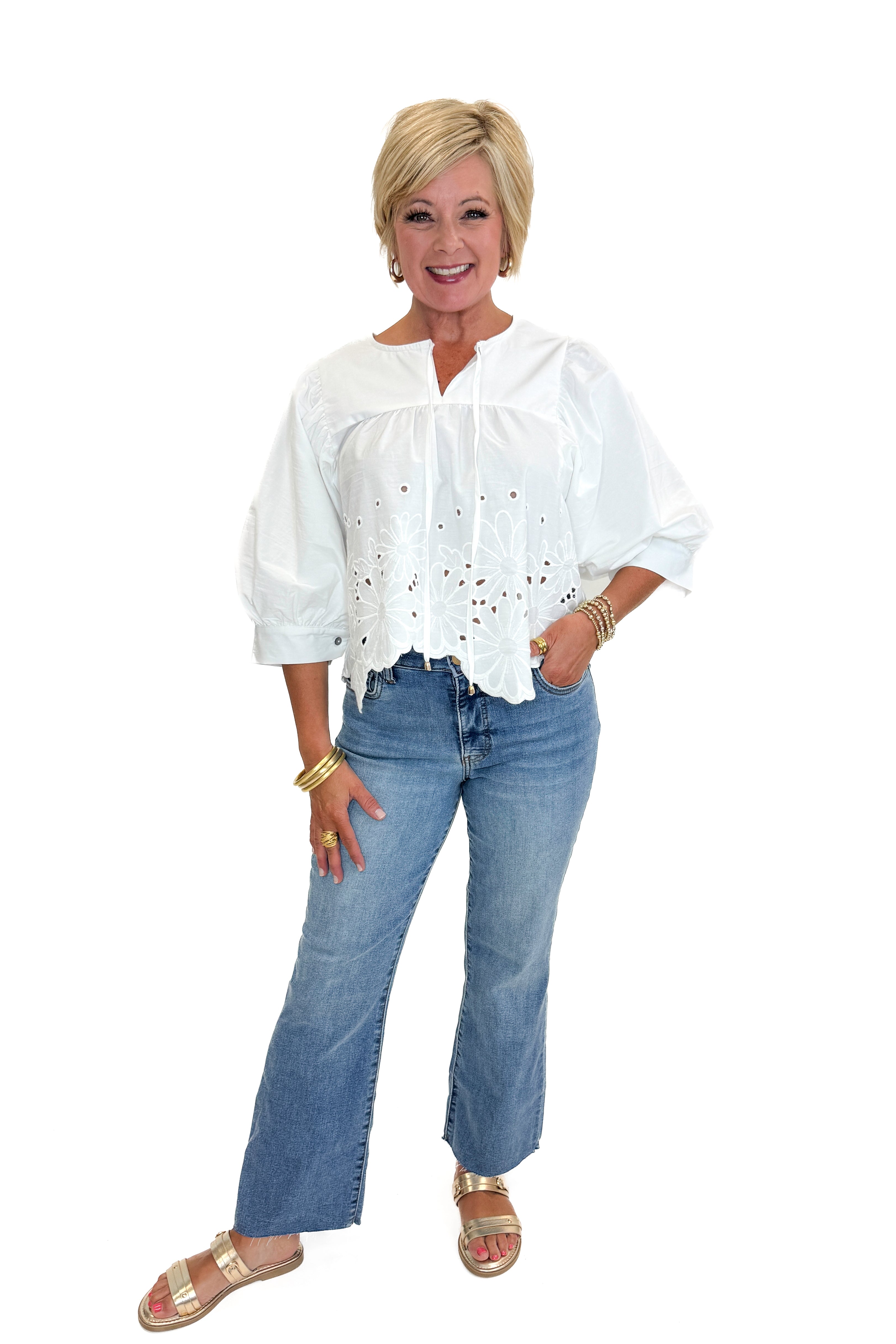 Front view of woman wearing Swagger Boutique’s White Puff Sleeve Eyelet Top with jeans against white studio background.