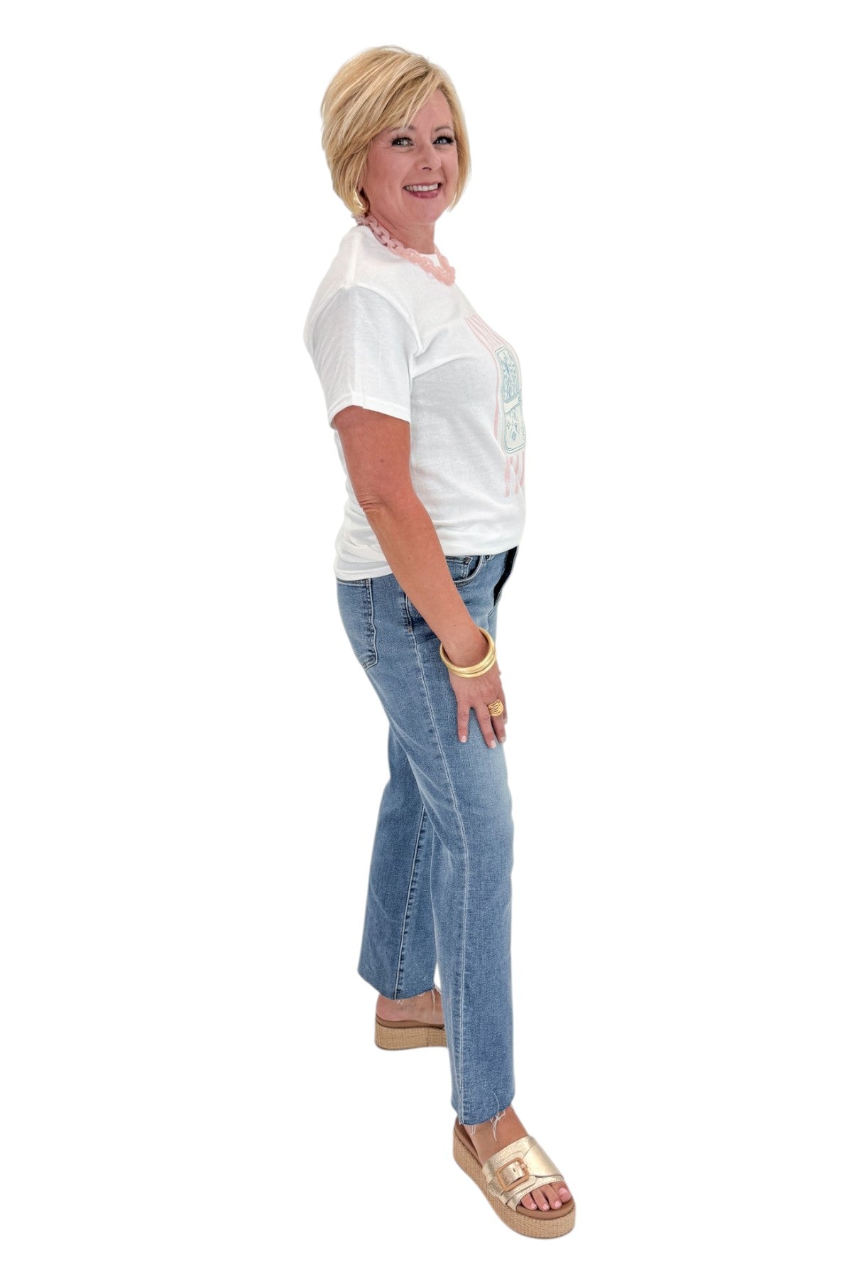 Side view of woman wearing Swagger Boutiqueβs White Sardine Graphic T-Shirt with jeans against white studio background.