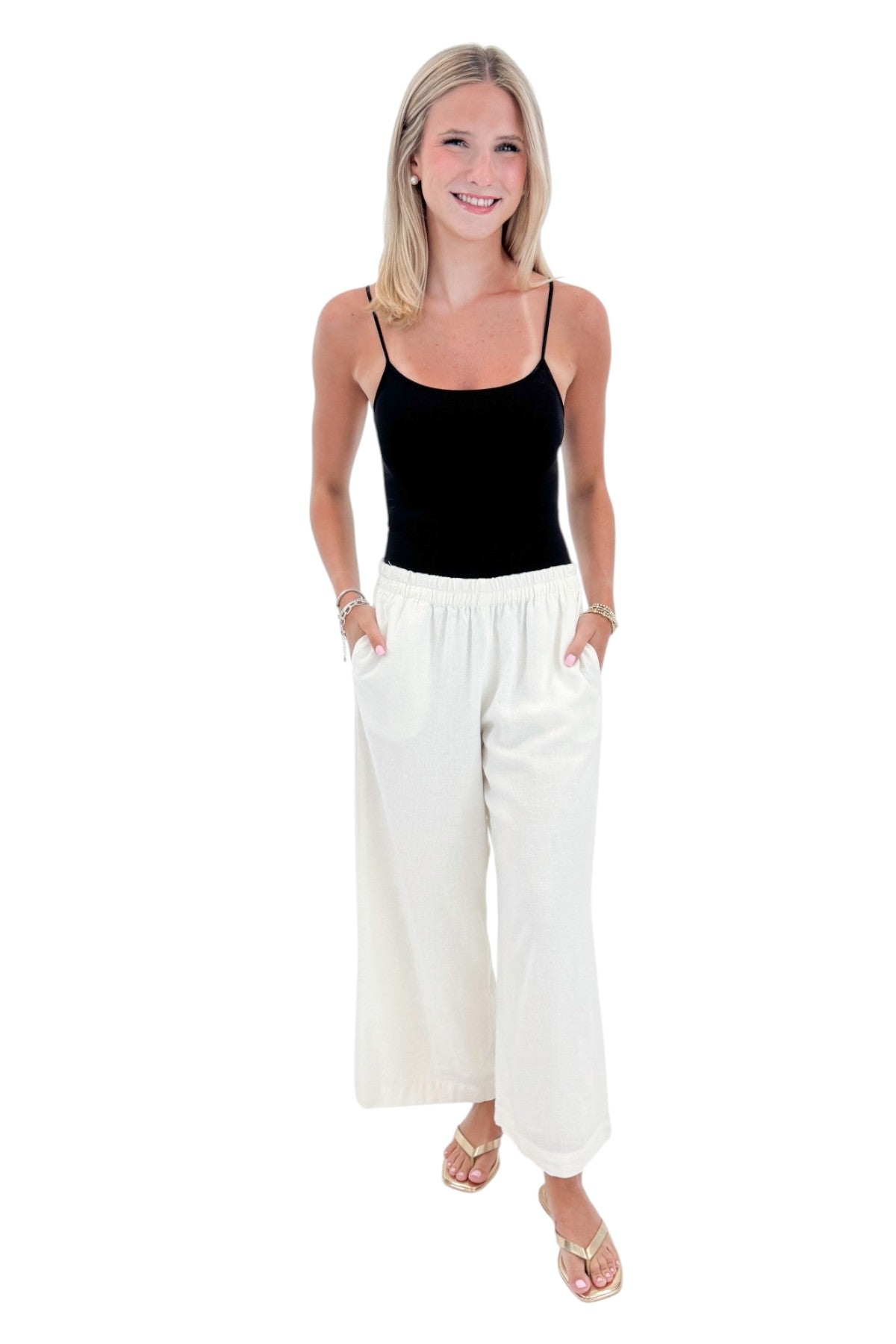 Front view of woman wearing Swagger Boutiqueβs White Scout Linen Pants by Z Supply with top against white studio background.