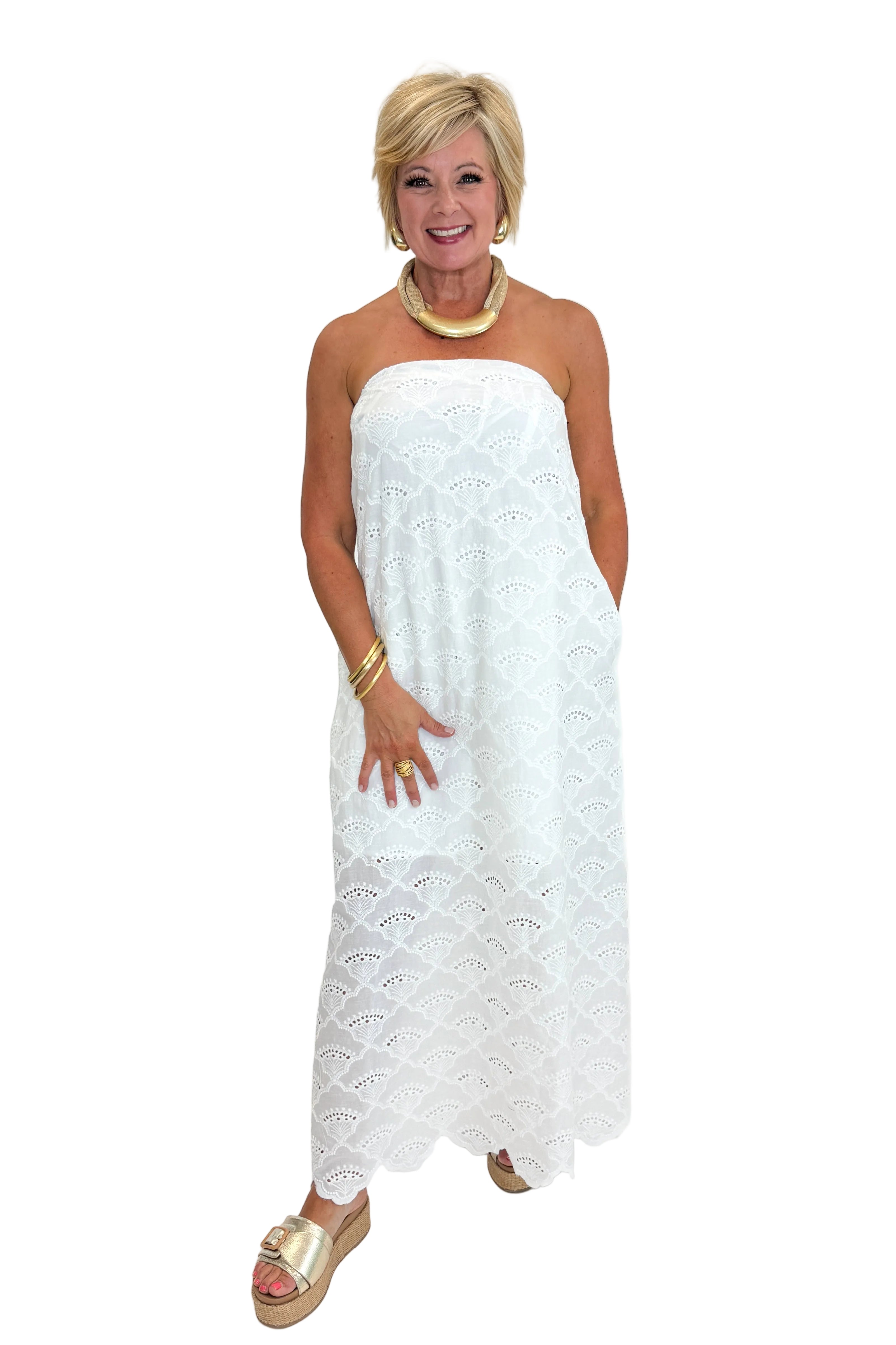 Front view of woman wearing Swagger Boutiqueβs White Strapless Eyelet Midi Dress by Entro with sandals against white studio background.