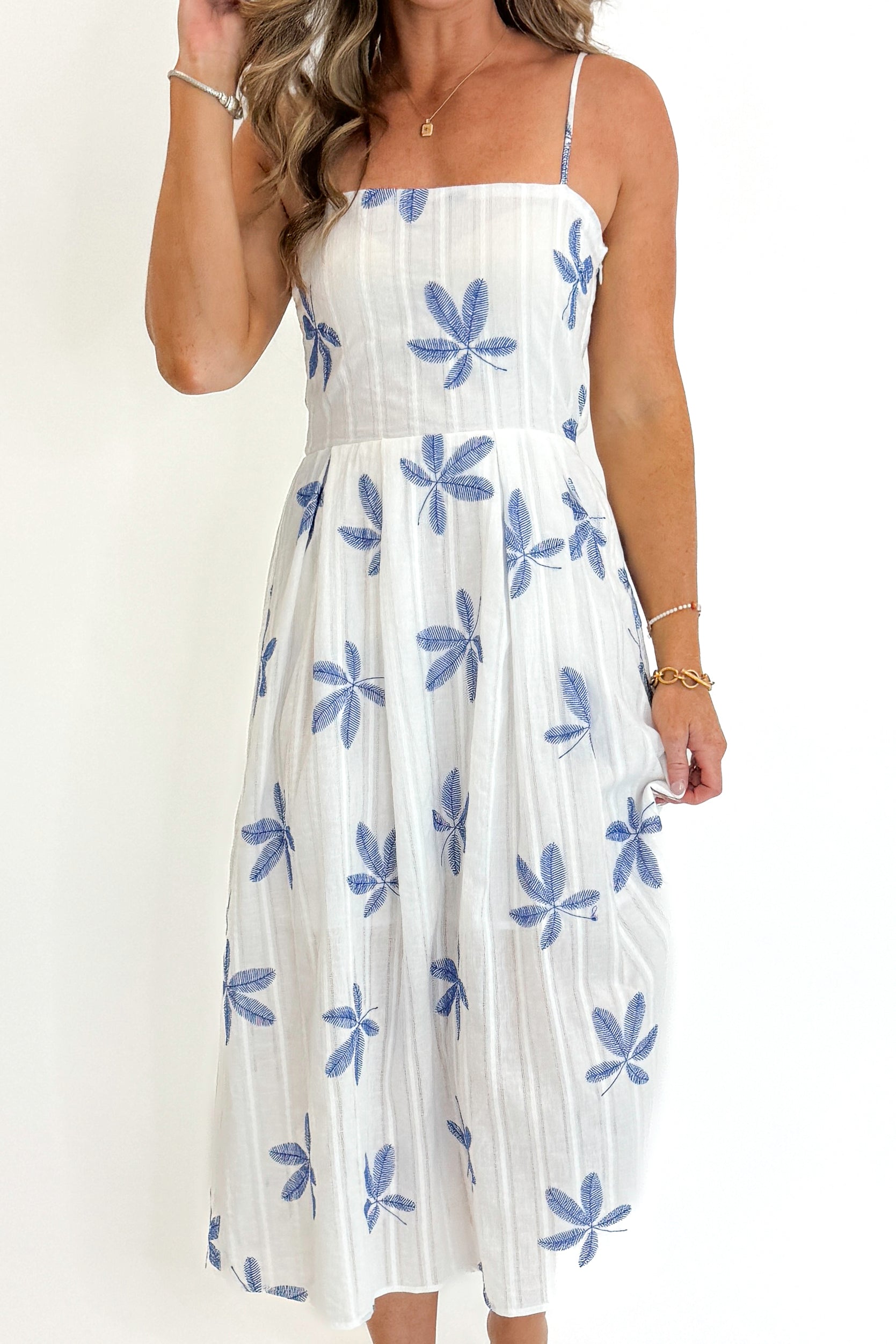 Front detail view of woman wearing Swagger Boutiqueβs White With Blue Embroidery Midi Dress against white studio background.