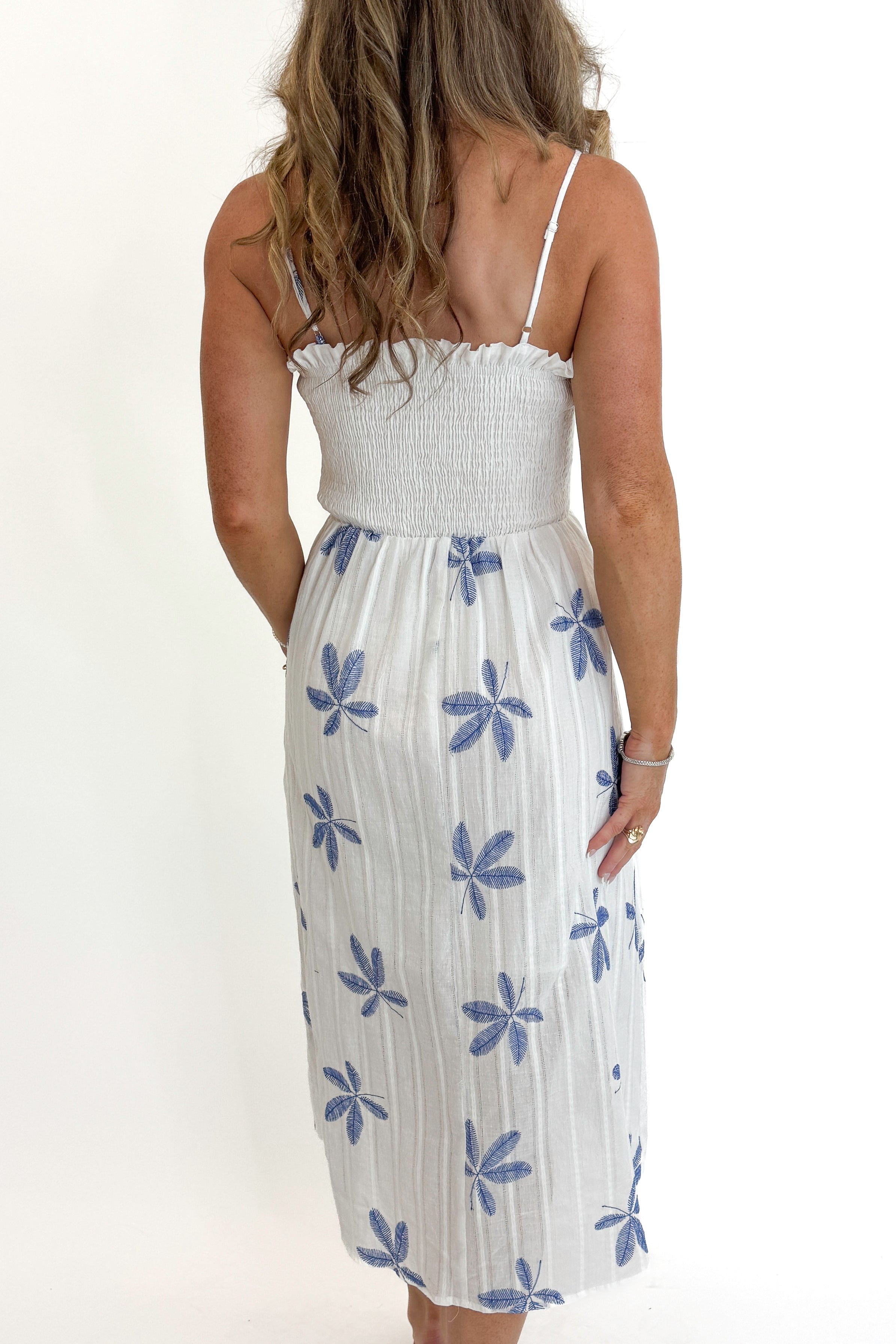 Back detail view of woman wearing Swagger Boutiqueβs White With Blue Embroidery Midi Dress against white studio background.