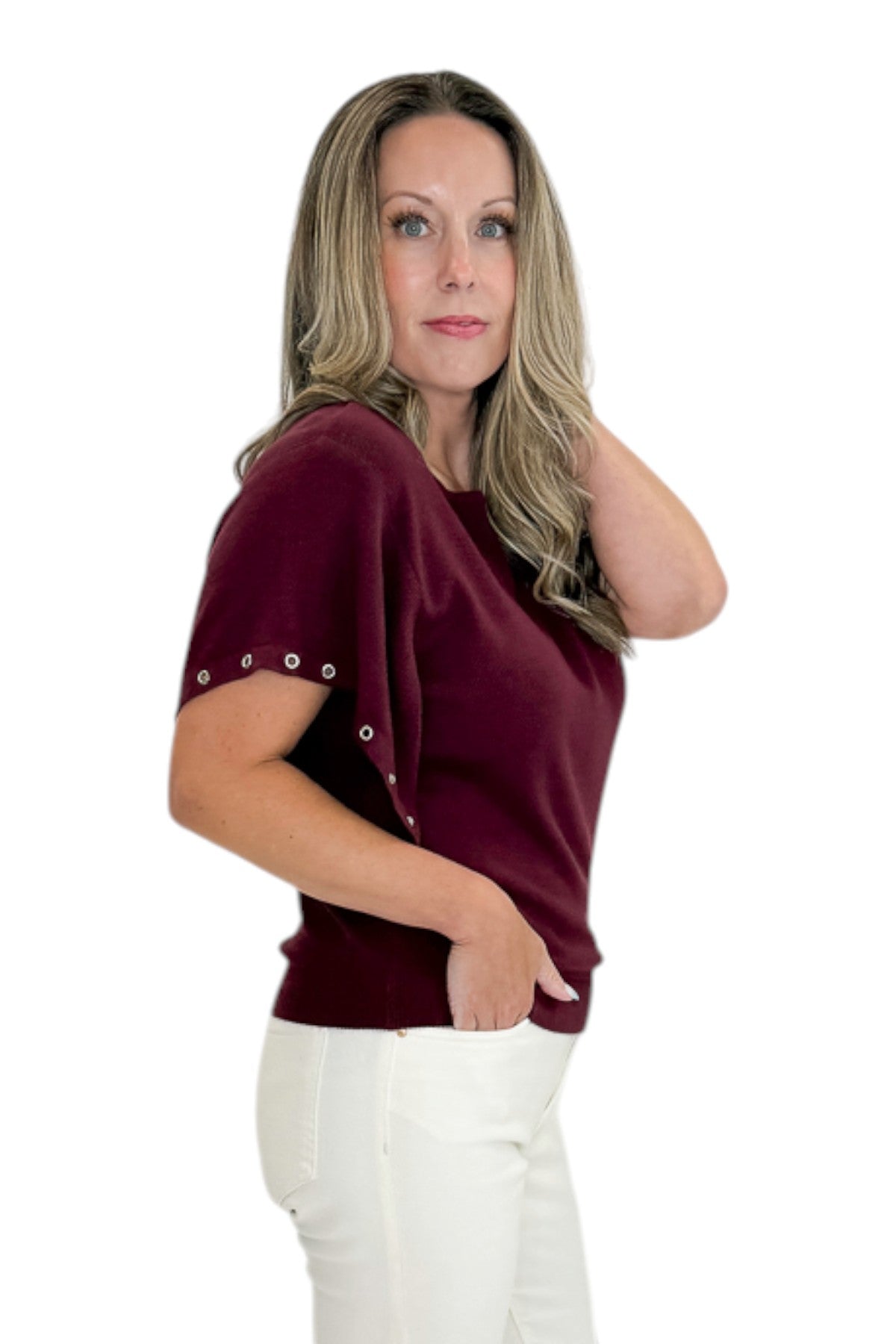 Side view of woman wearing Swagger Boutiqueās Wine Grommet Sleeve Knit Top by Entro with jeans against white studio background.