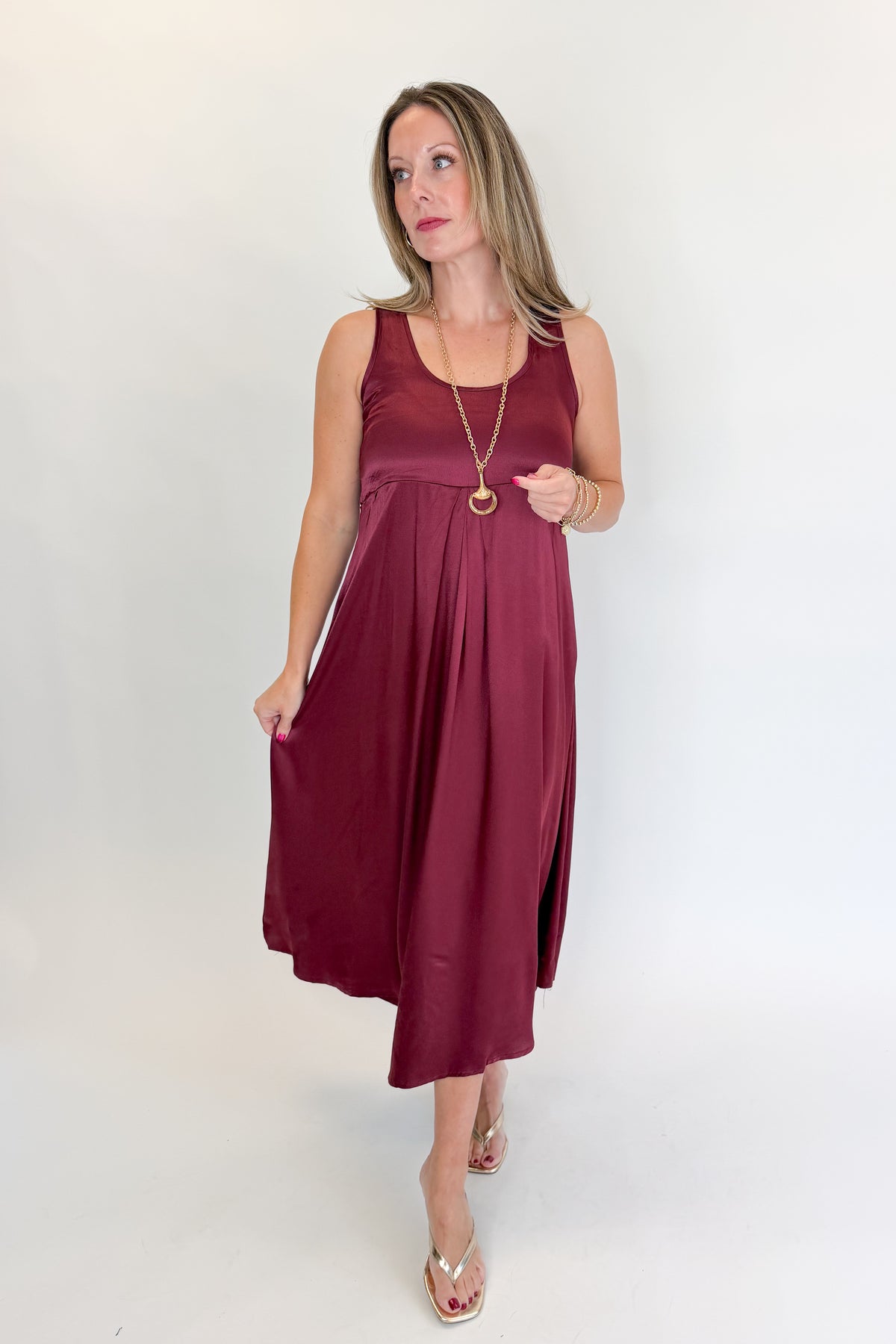 Front view of woman wearing Swagger Boutique’s Wine & Leopard Layered Midi Dress with heels against white studio background.