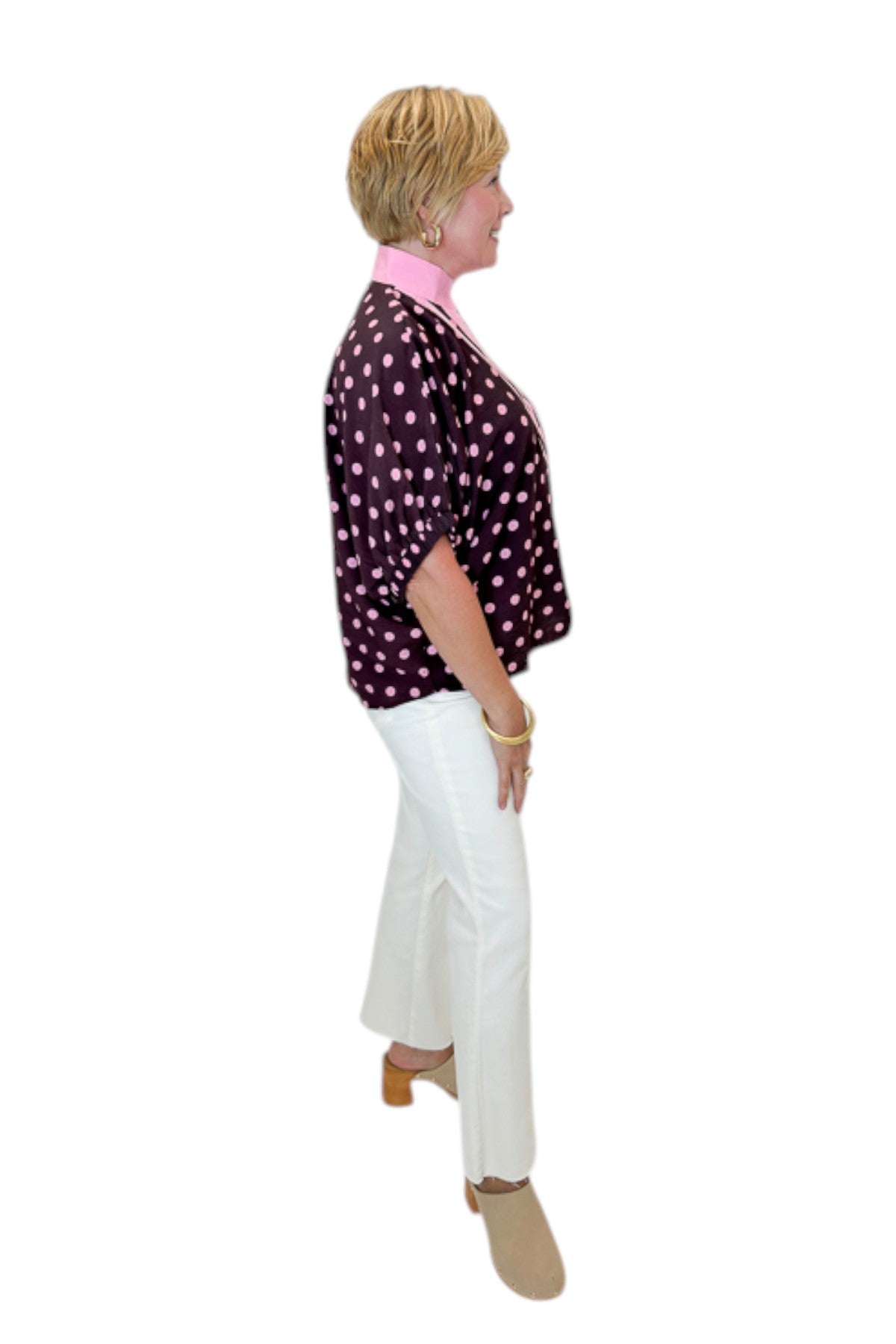 Side view of woman wearing Swagger Boutique’s Wine & Pink Polka Dot Dolman Sleeve Top by Entro with jeans against white studio background.