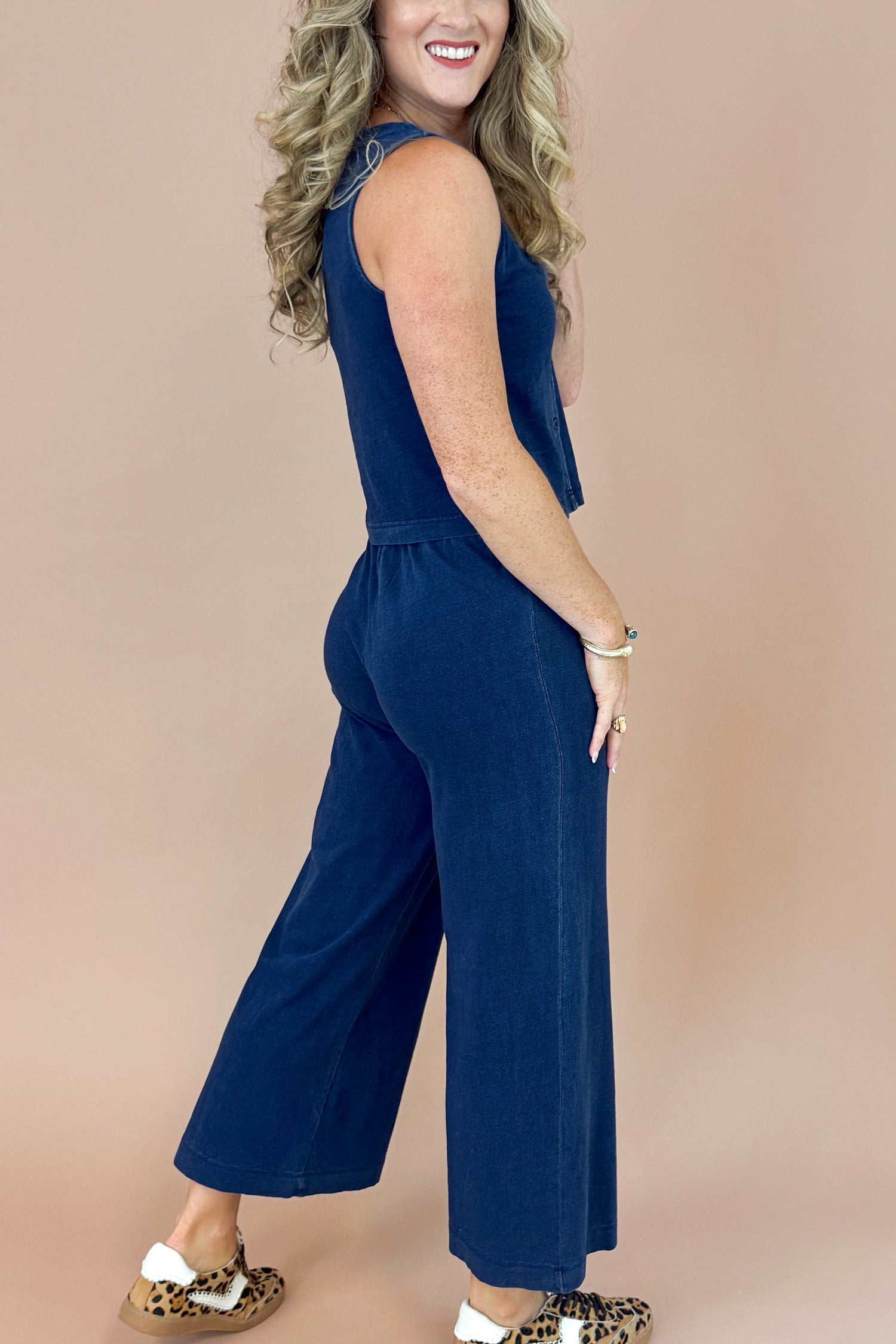 Woman wearing a navy blue jumpsuit against a beige background