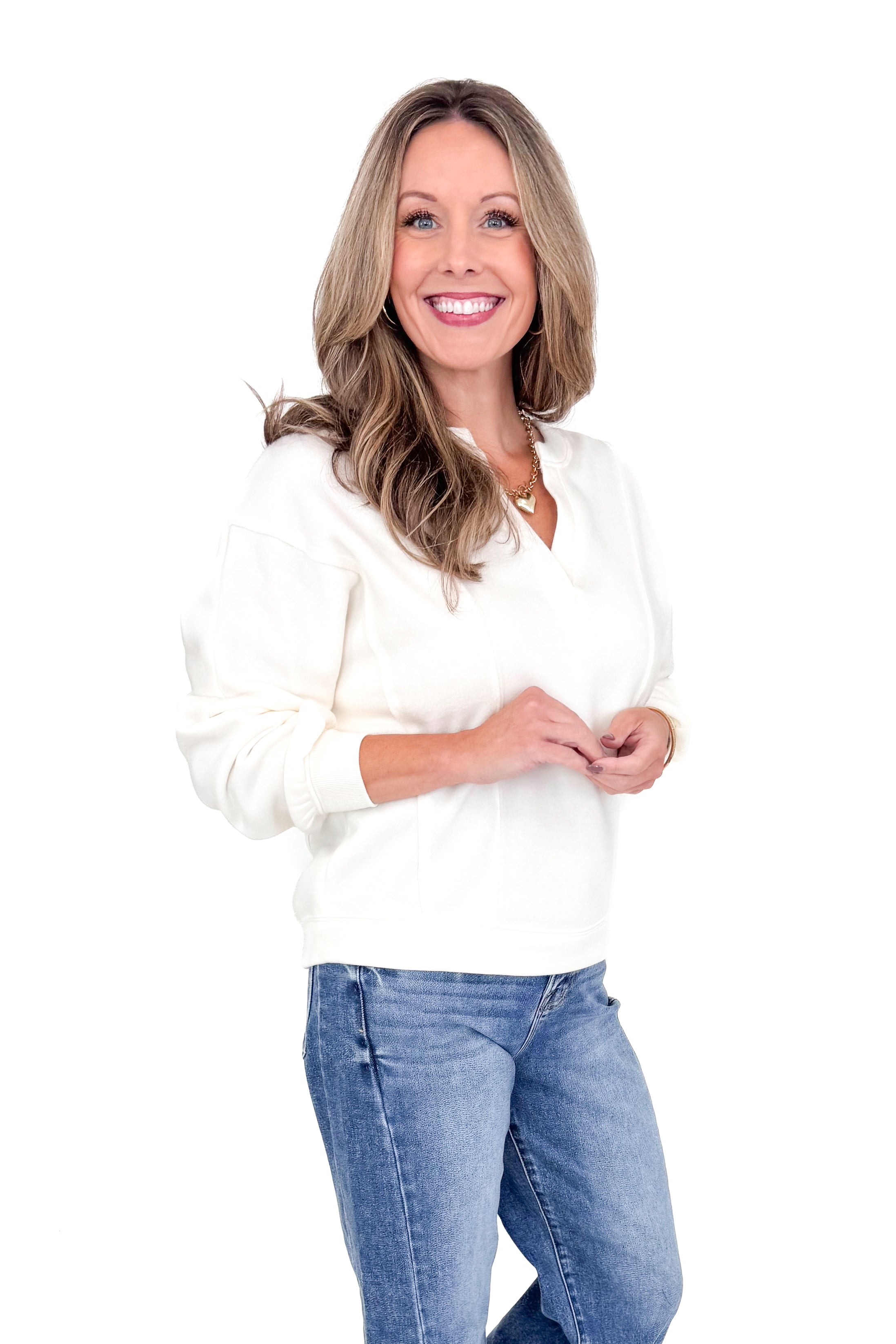 Side view of woman wearing Z Supply cream top with jeans against white studio background.
