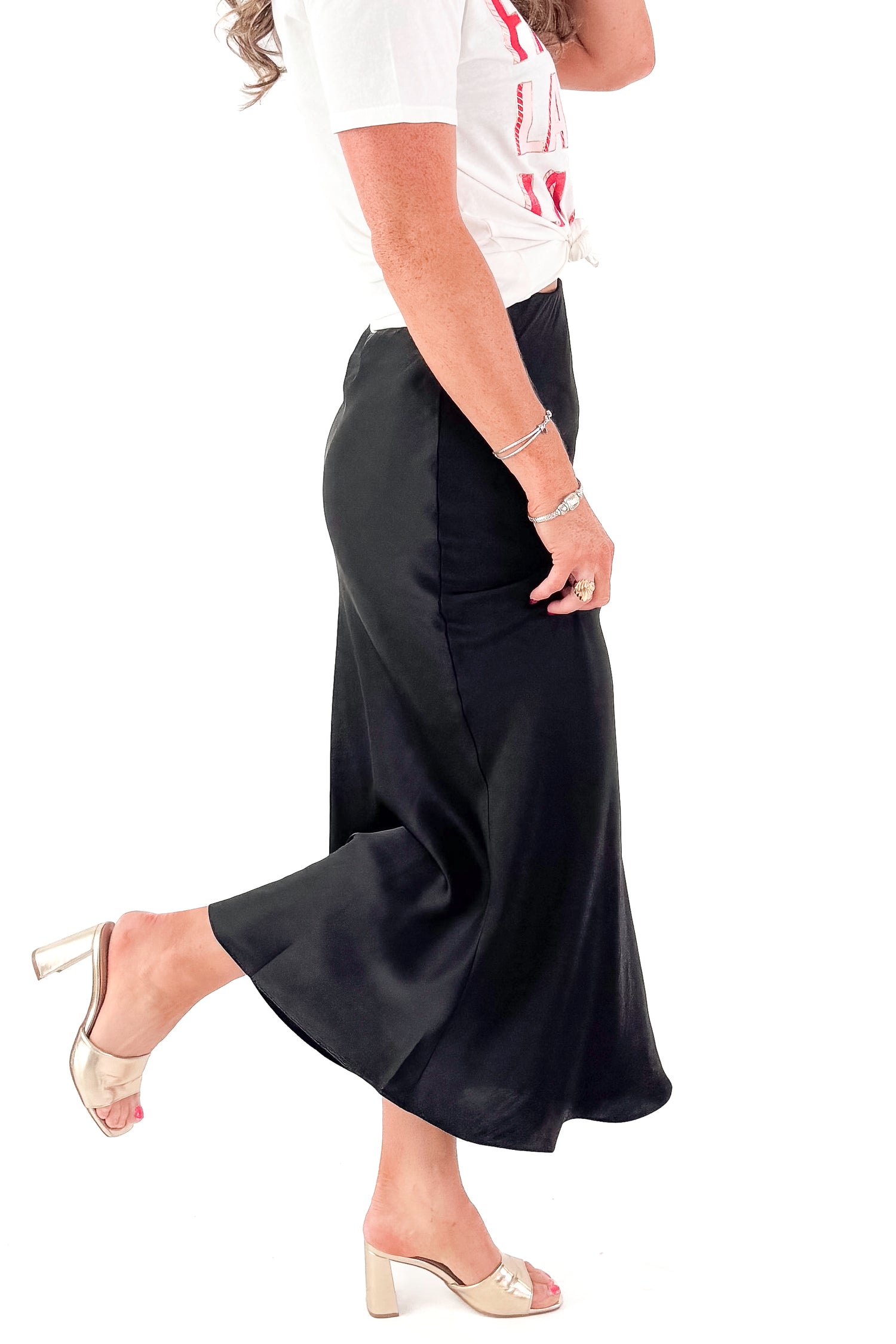 Side view of woman wearing t-shirt and black skirt by Z Supply against white studio background.